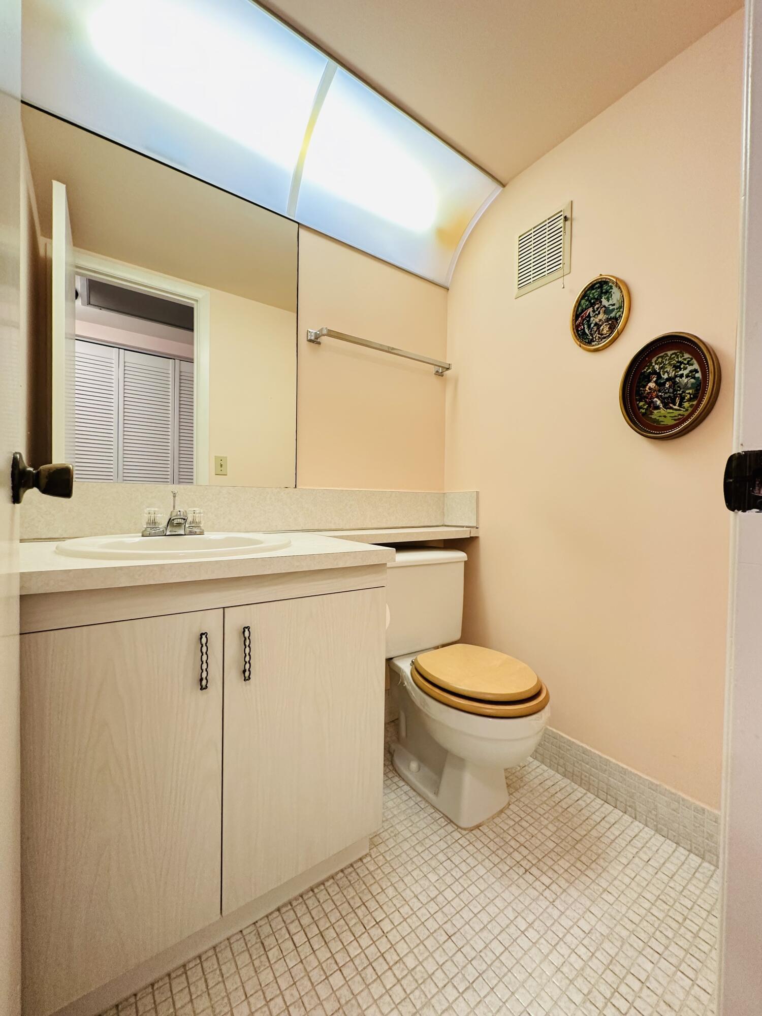 Bathroom featuring a vanity with light-tone cabinetry and an integrated sink, a full-width wall mirror, recessed lighting with a diffuser panel, and ceramic tile flooring