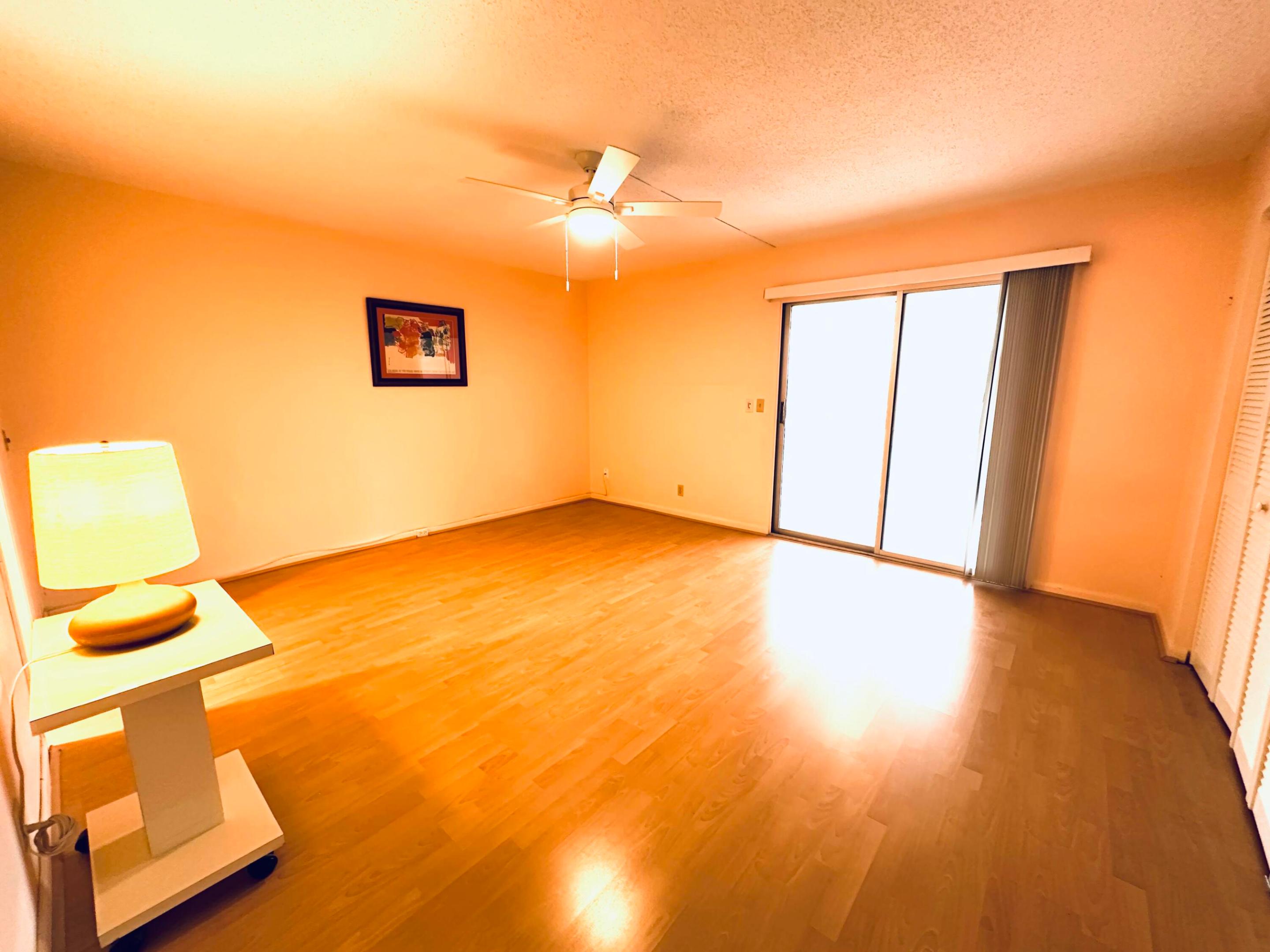 Laminate flooring, ceiling fan with integrated lighting, and glass sliding doors with vertical blinds