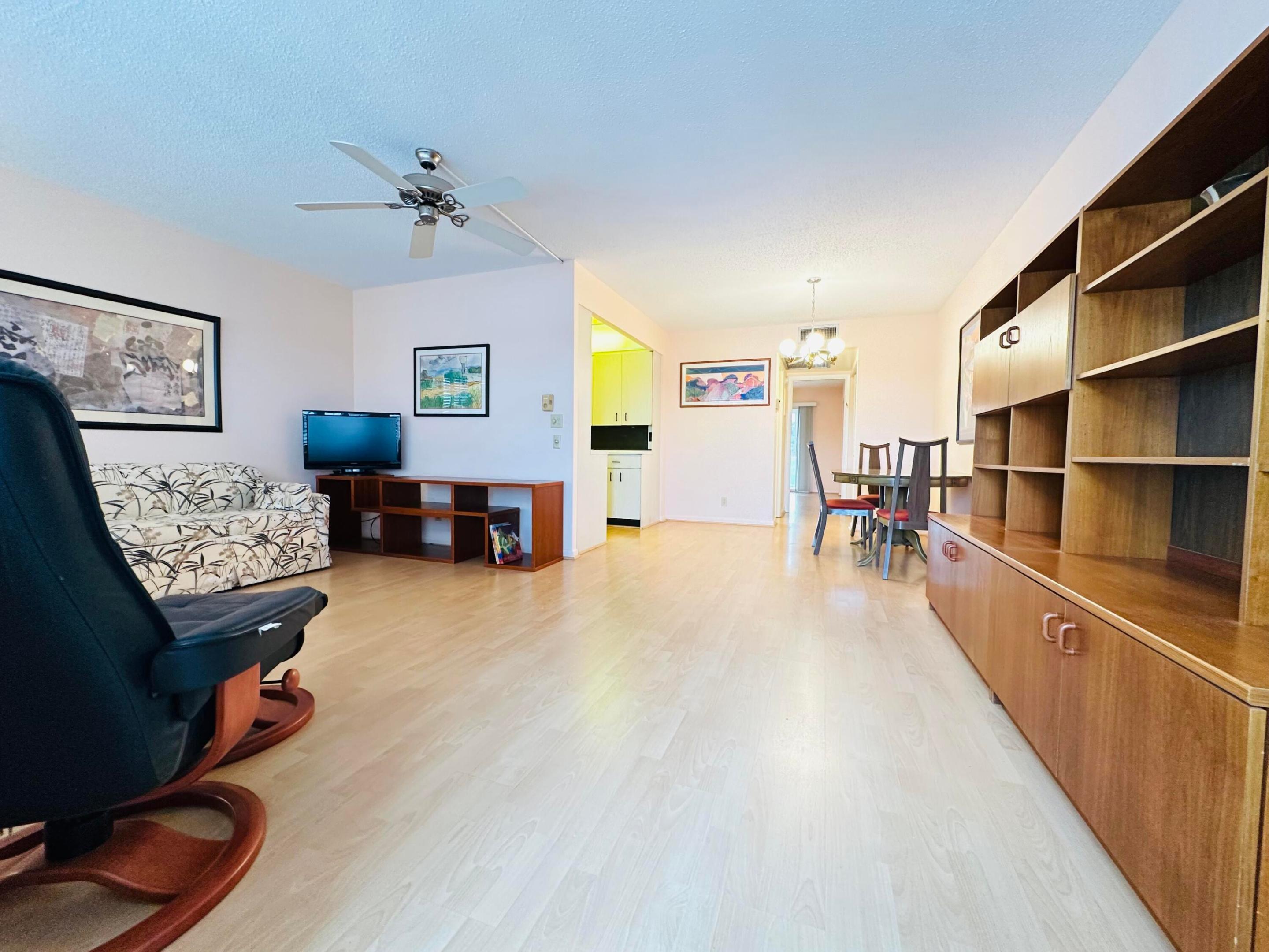 Open-concept living space featuring laminate flooring, furnished, and a ceiling fan with integrated lighting Open-concept living space featuring laminate flooring, furnished, and a ceiling fan with integrated lighting