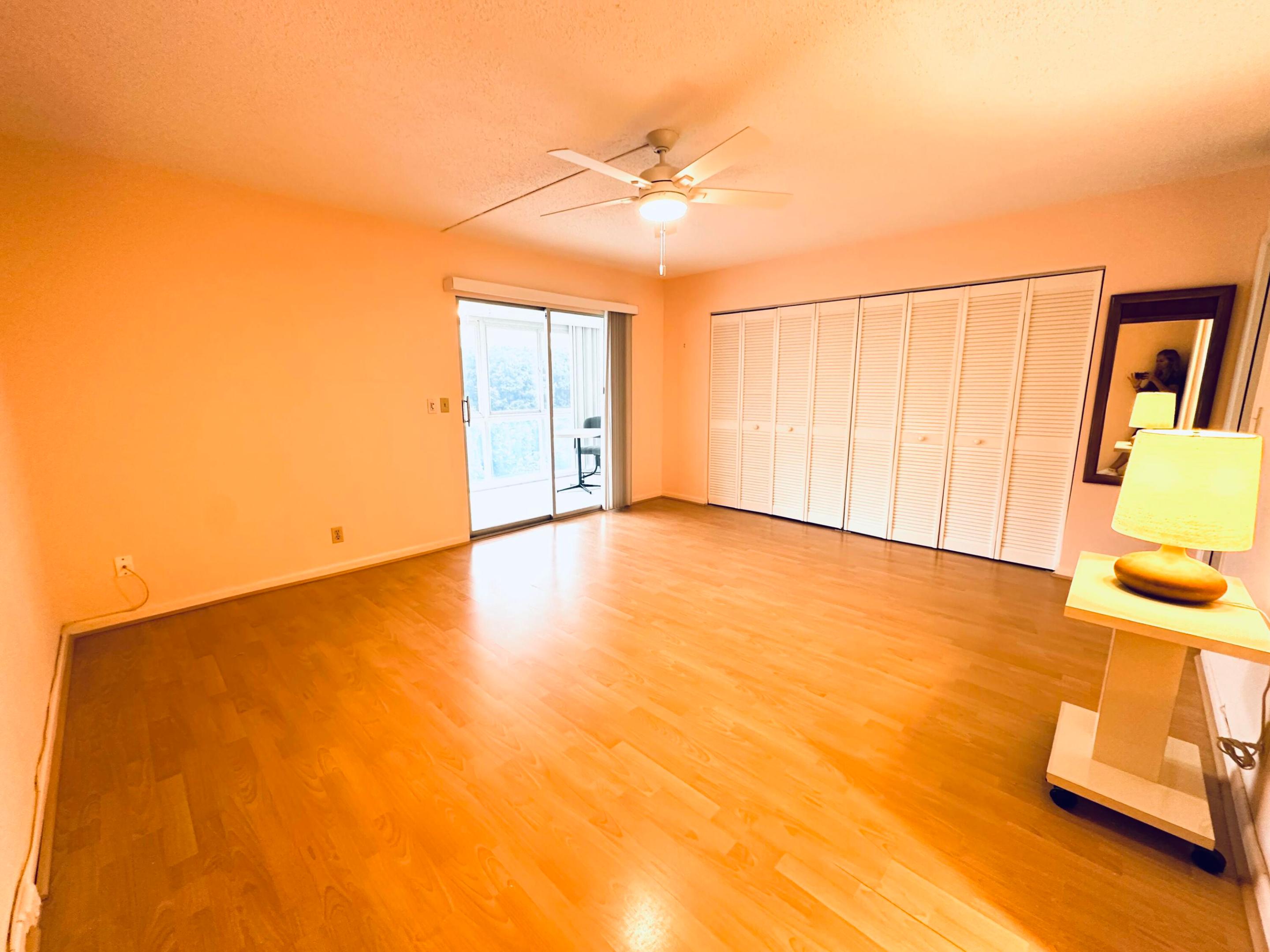 Spacious interior featuring wood-finish flooring, white louvered-panel closet doors, a ceiling-mounted light fixture, and a sliding glass door