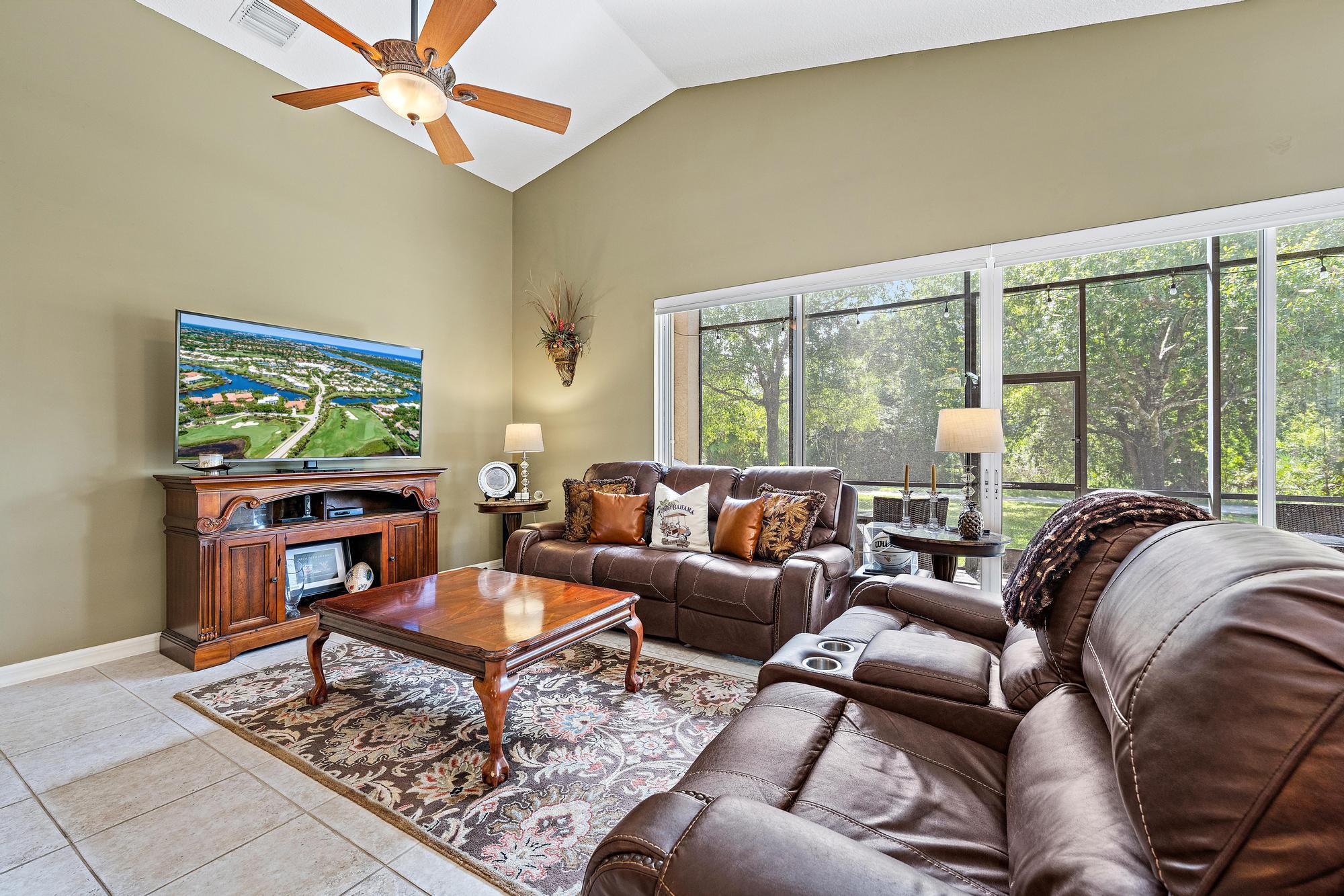 Vaulted ceilings, large-format tile flooring, and oversized sliding glass doors with custom remote controlled blinds opening to a screened lanai