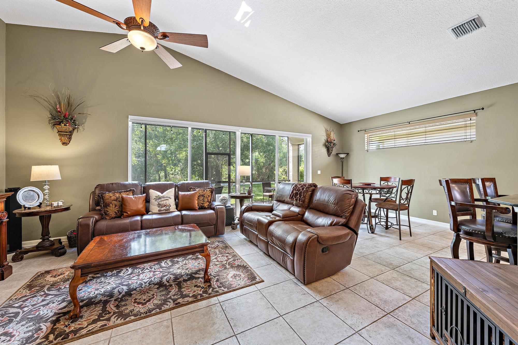 Vaulted ceilings, large-format tile flooring, and oversized sliding glass doors with custom remote controlled blinds opening to a screened lanai