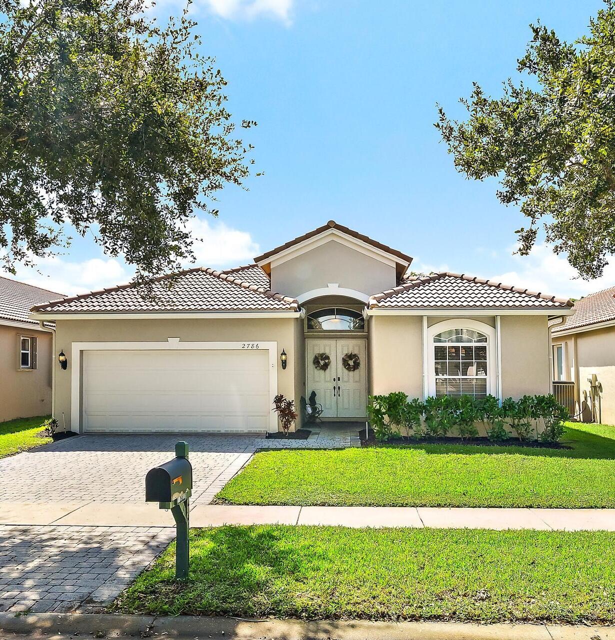 Stucco exterior featuring a tiled roof, arched entryway, double-door entrance, and a paved driveway