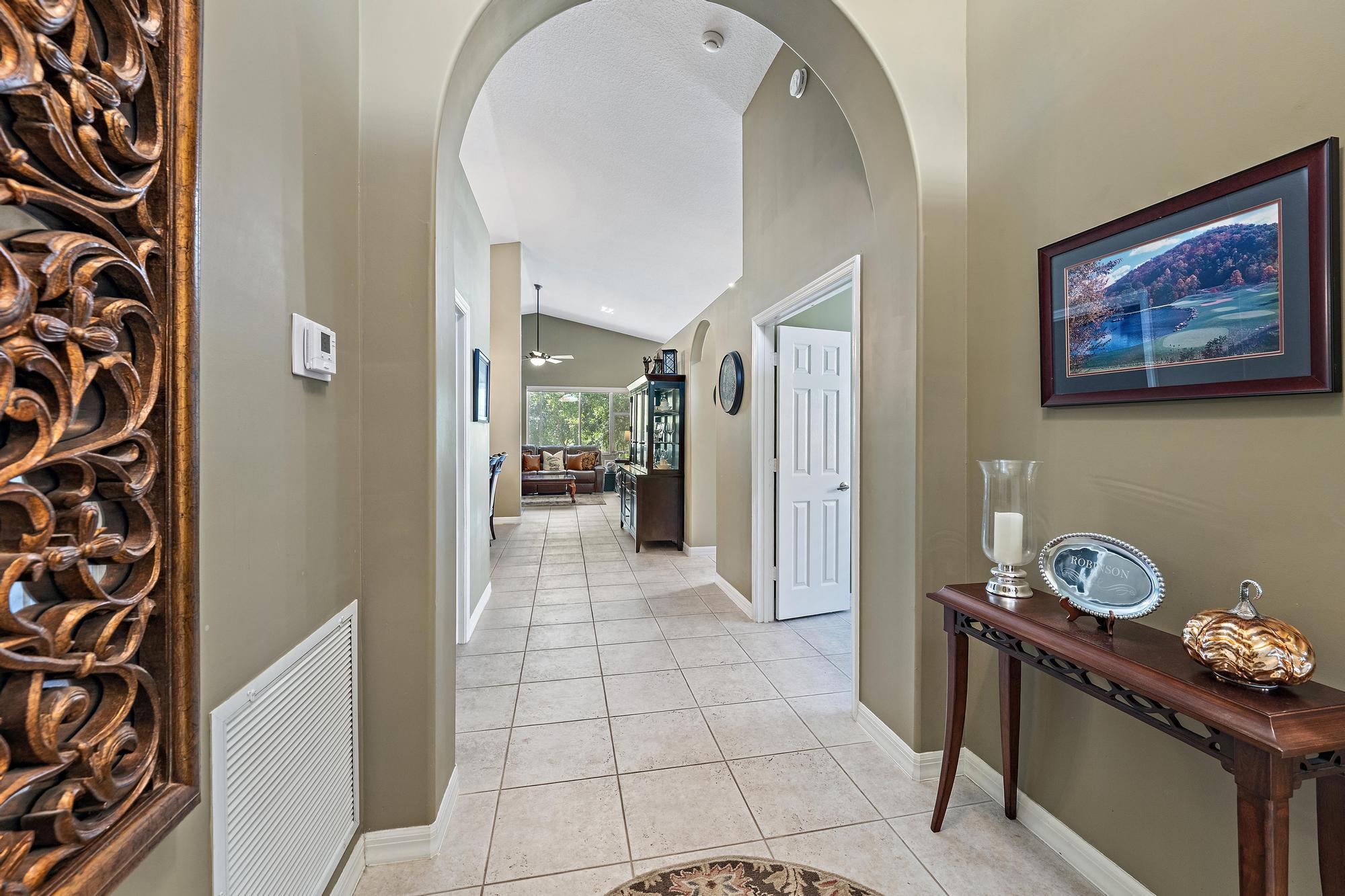 Interior foyer featuring a high vaulted ceiling, arched architectural detailing, and neutral tile flooring