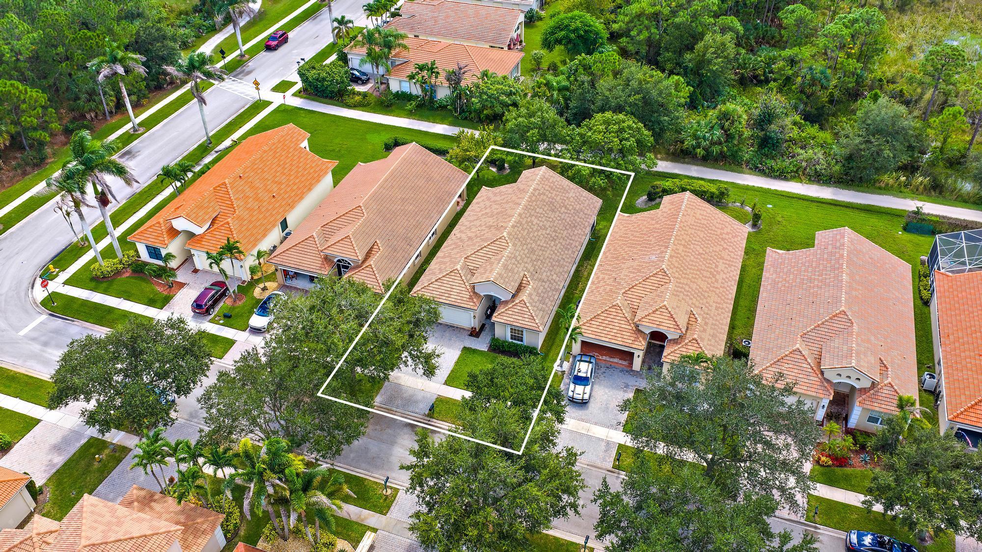 Single-story residence featuring tiled roof, paved driveway, two-car garage, and established landscaping