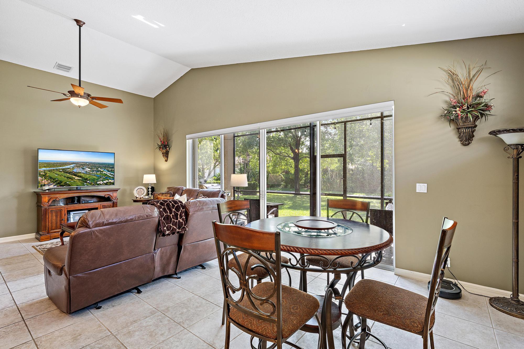 Vaulted ceilings, large-format tile flooring, and oversized sliding glass doors with custom remote controlled blinds opening to a screened lanai