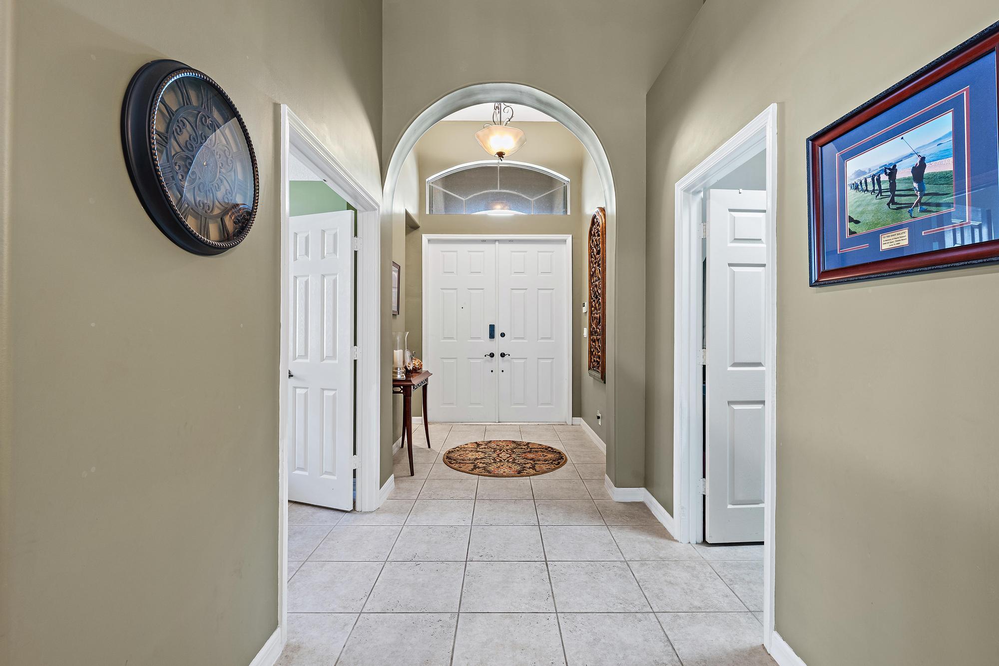 Foyer featuring arched architectural detailing, double-door entry, transom window, and tile flooring