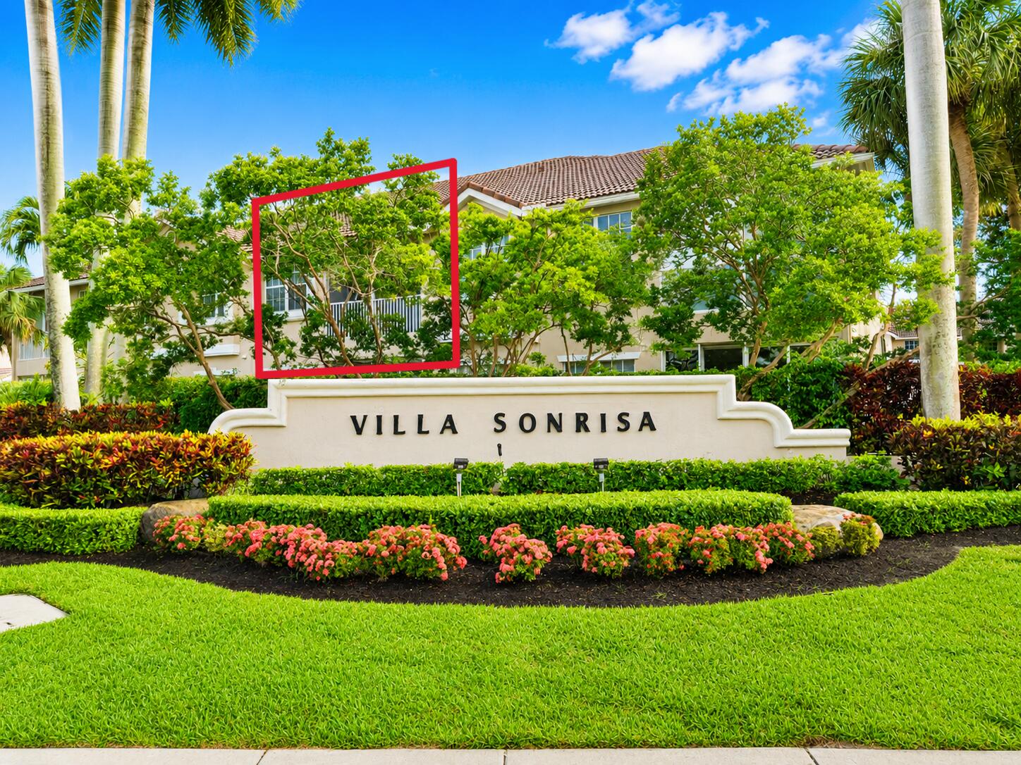 Stucco exterior facade featuring a tile roof, screened balcony, and mature tropical landscaping