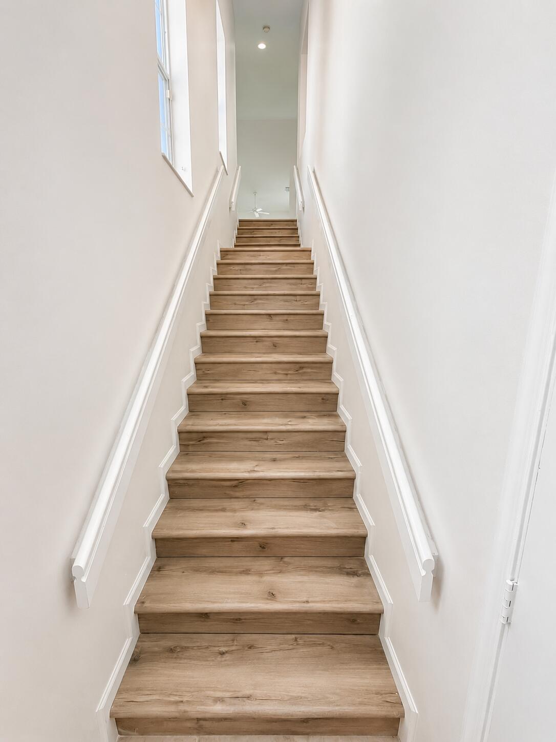 Staircase featuring wood-finish treads and white-painted handrails