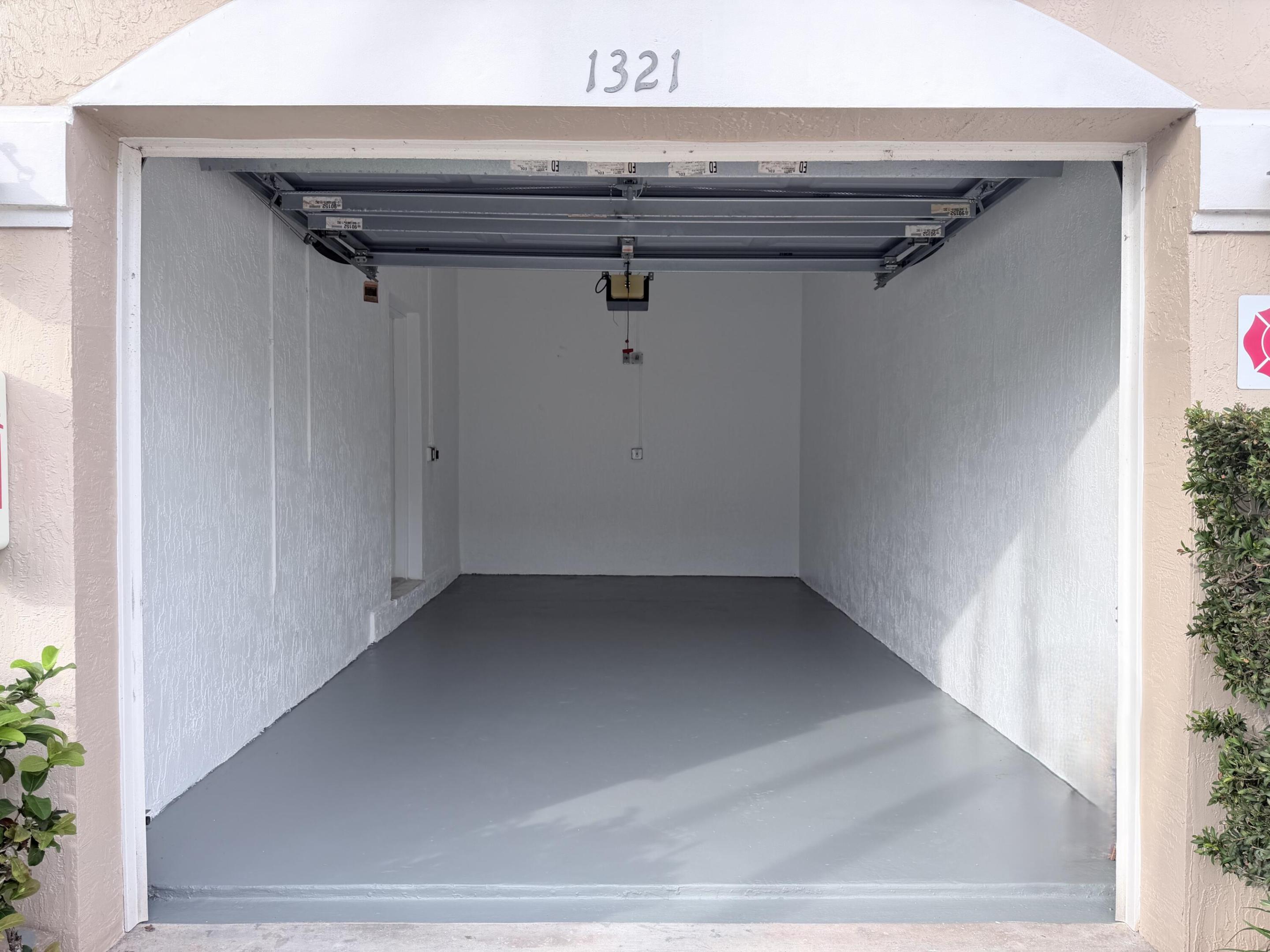 Attached garage featuring smooth white walls, high-gloss gray epoxy flooring, and an automated overhead door opener