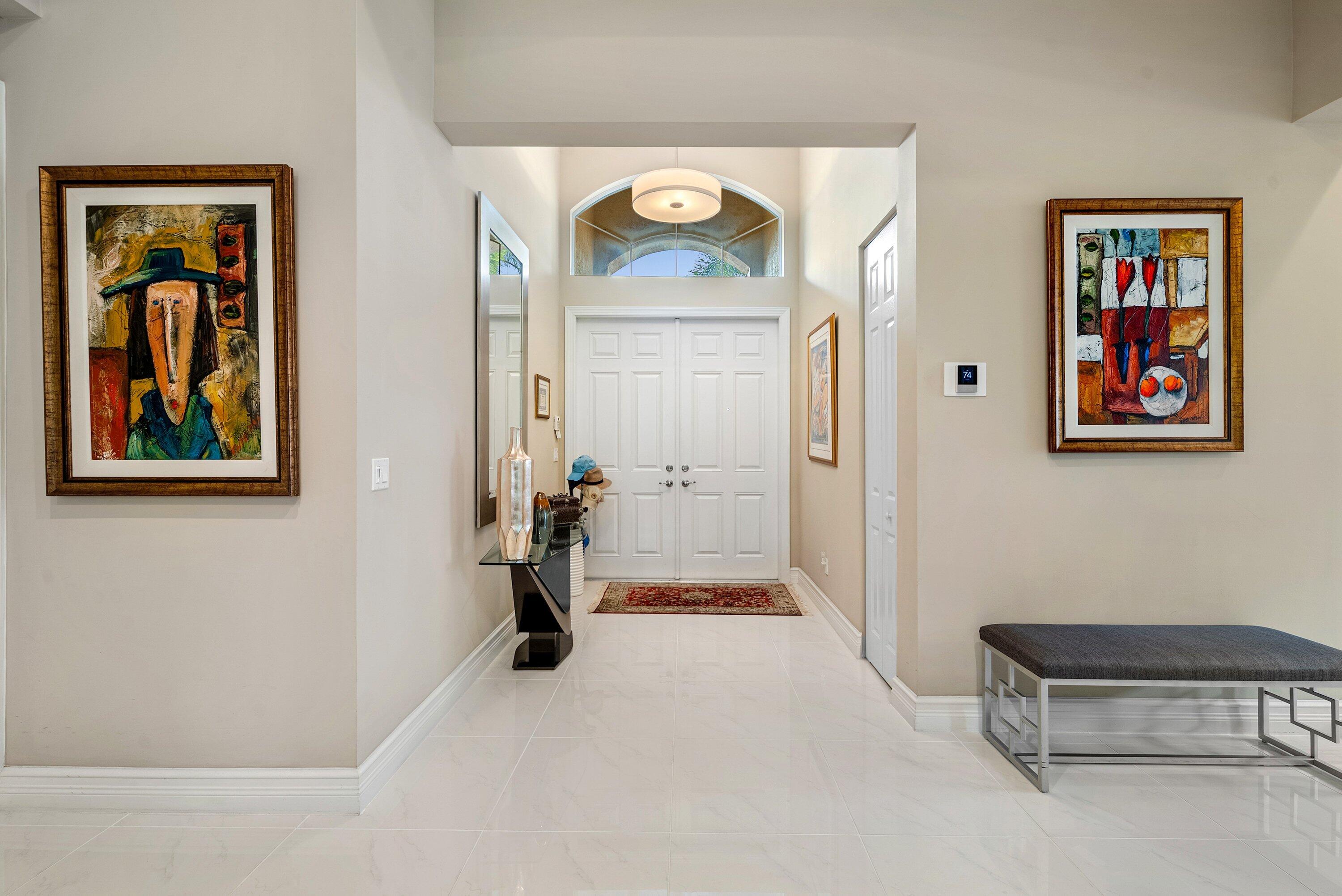 Foyer featuring double-door entry, arched transom window, pendant lighting, and polished stone-finish flooring Foyer featuring double-door entry, arched transom window, pendant lighting, and polished stone-finish flooring