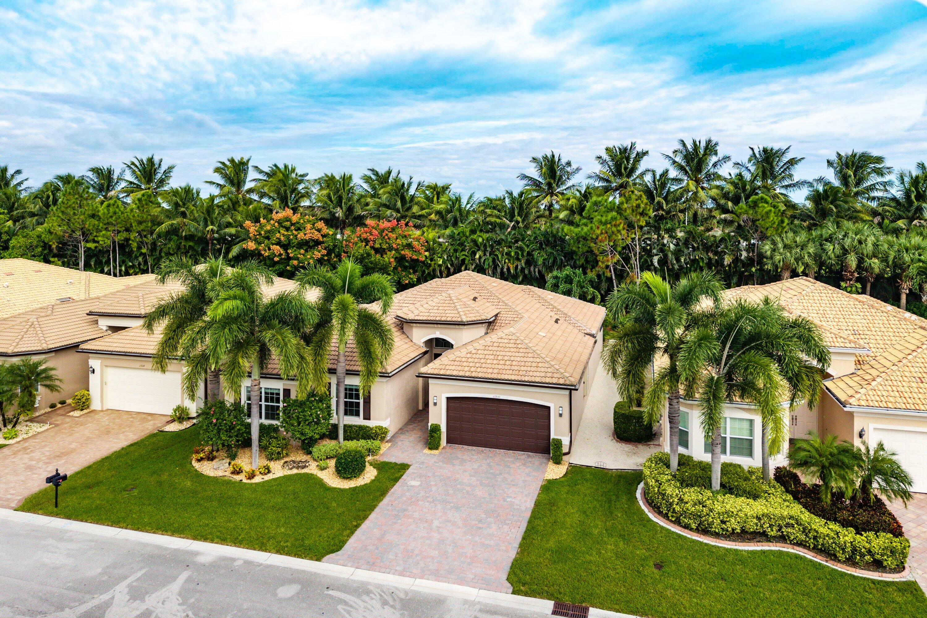 Single-story residence featuring a tile roof, neutral stucco exterior, paver driveway, multi-car garage, and established landscaping