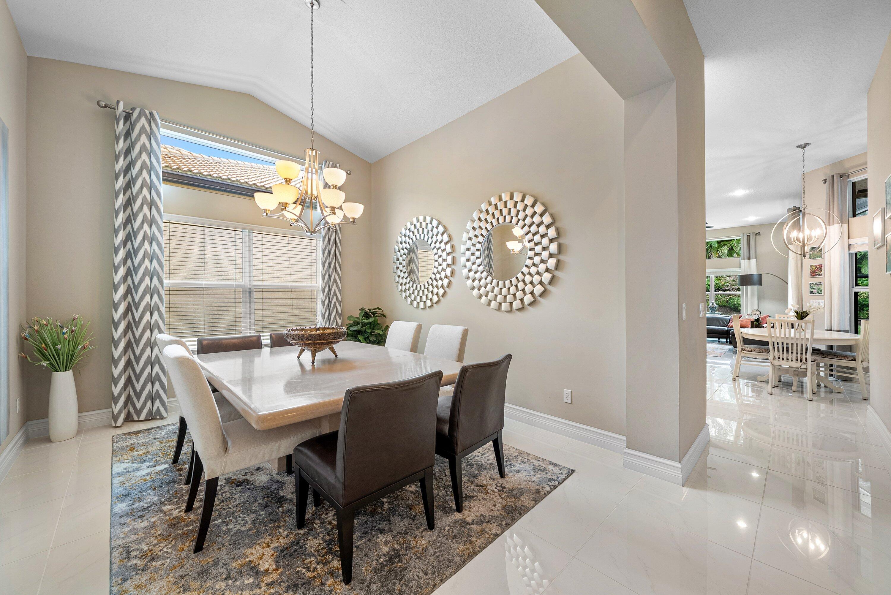 Dining area featuring vaulted ceilings, oversized tile flooring, and a multi-arm chandelier