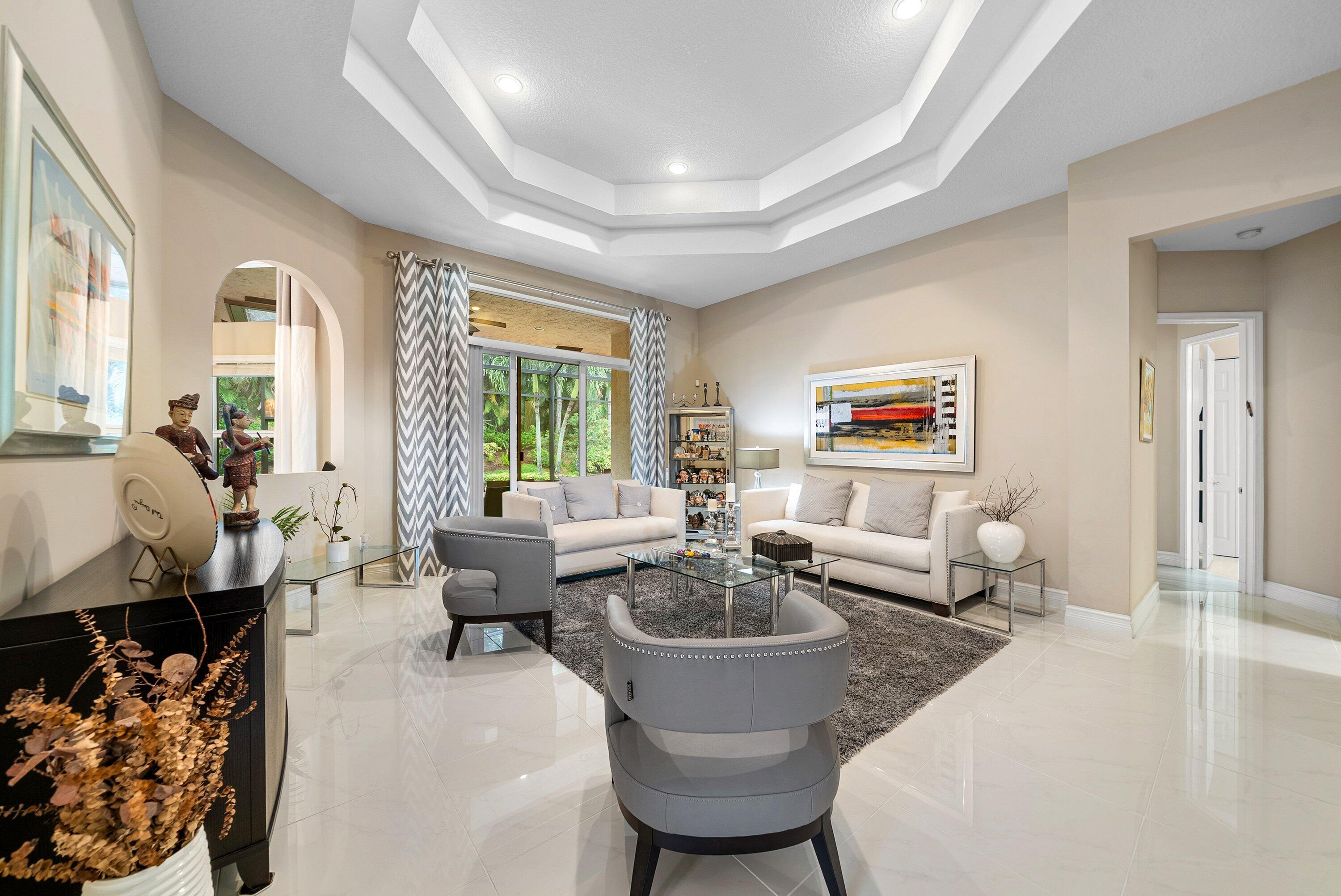 Tray ceiling with recessed lighting, large-format tile flooring, arched wall cutout, and sliding glass doors