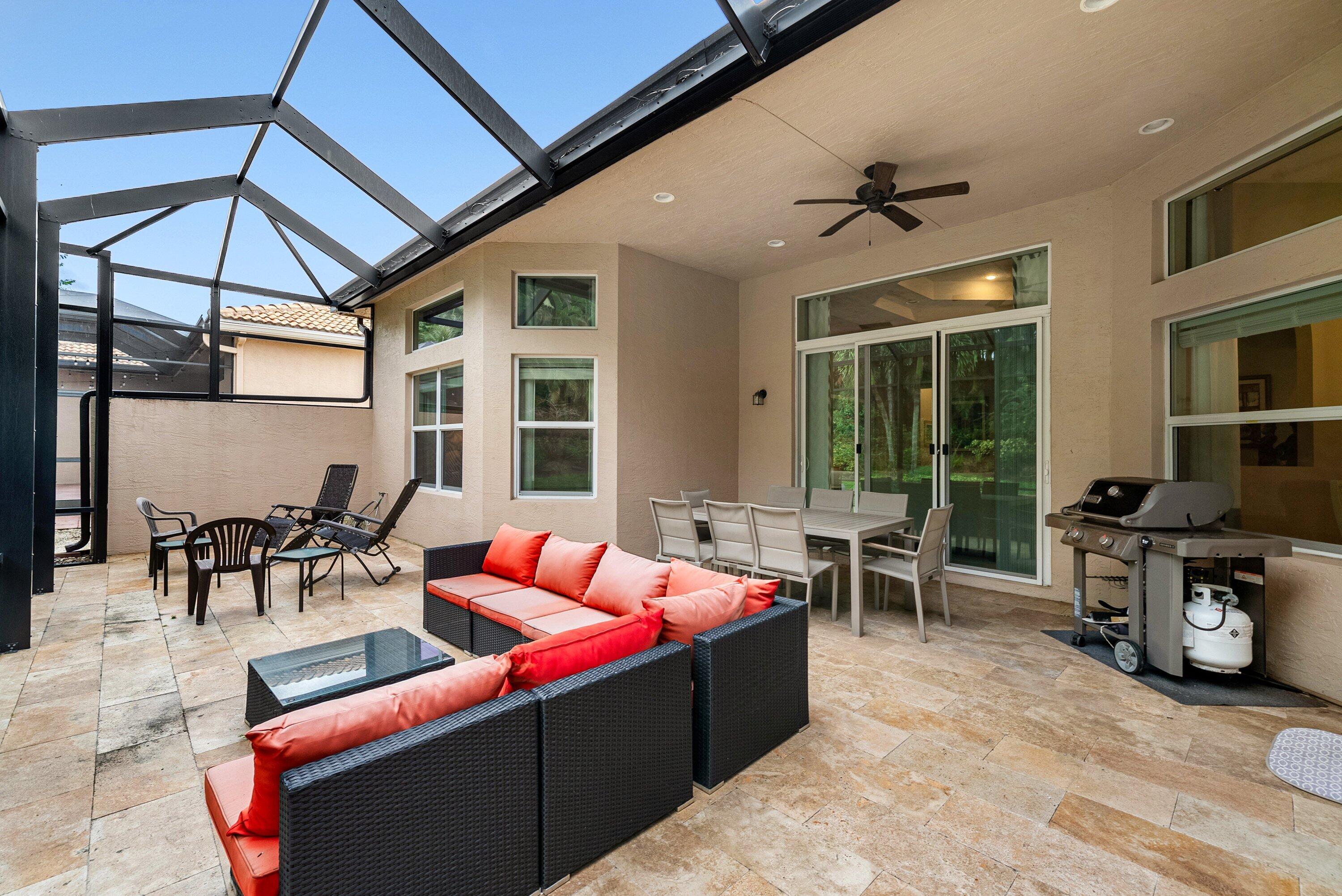 Covered outdoor patio featuring natural stone flooring, a screened-in aluminum enclosure, recessed lighting, and a ceiling fan