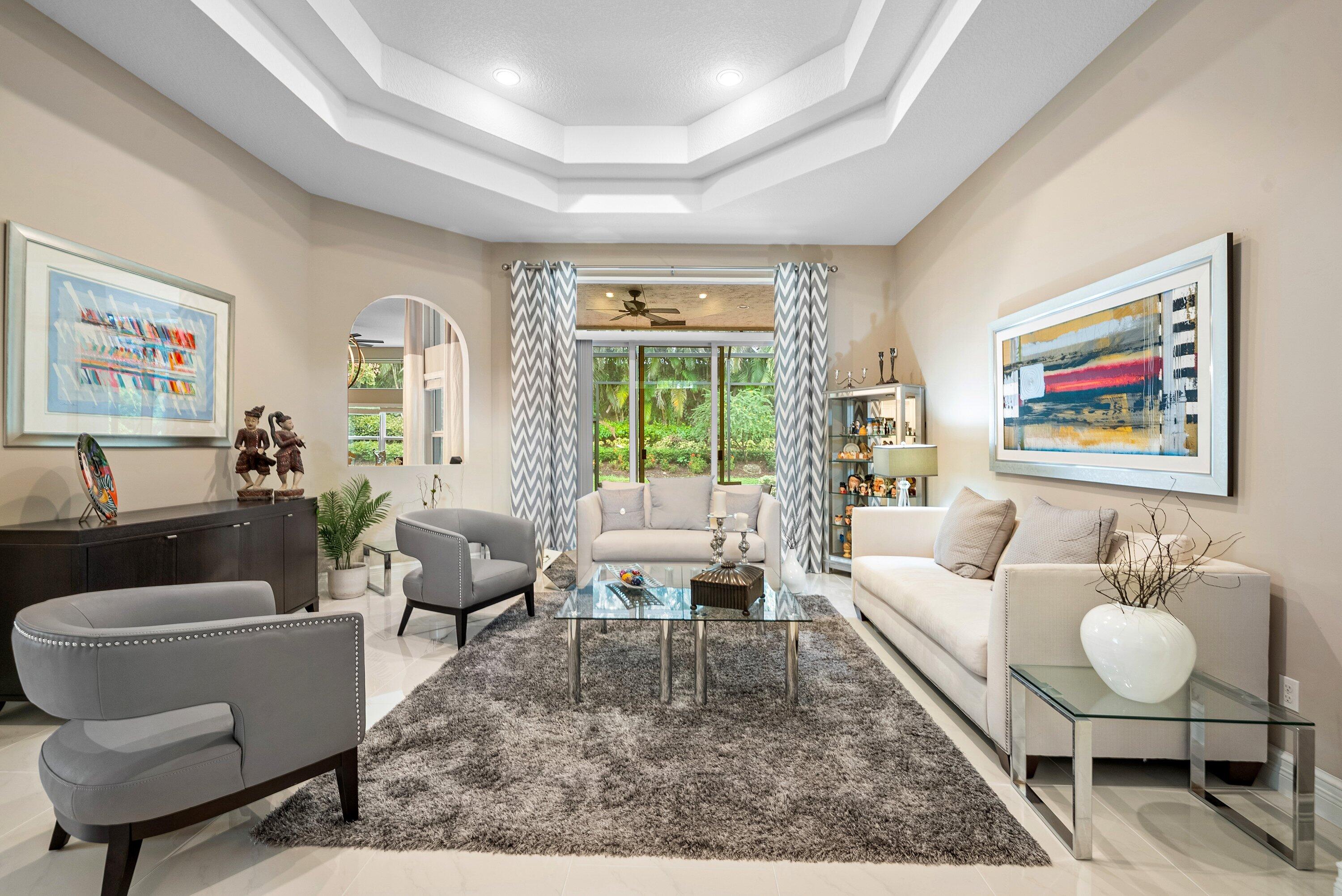 Tray ceiling with recessed lighting, large glass sliding doors, polished tile flooring, and an arched entryway
