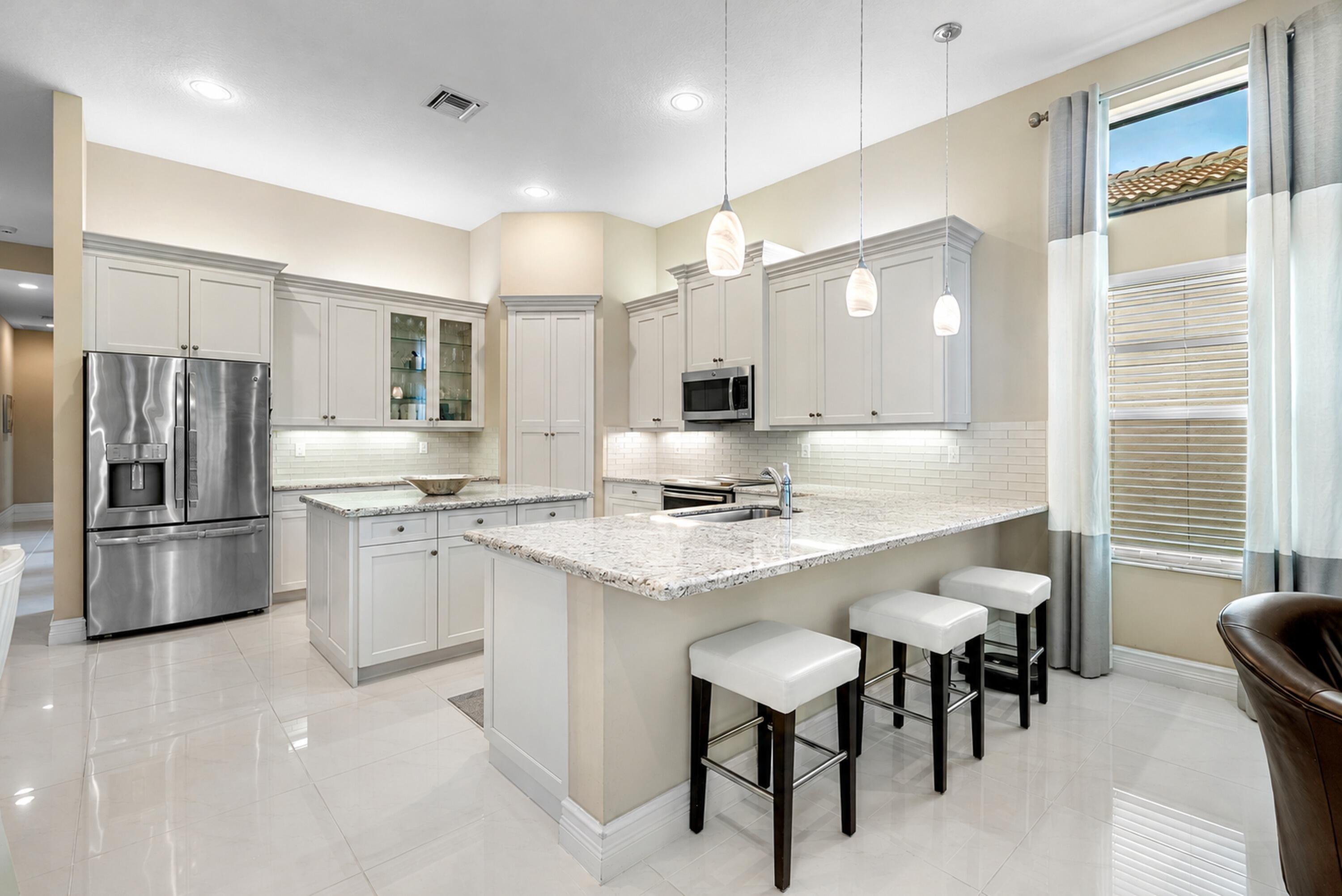 Kitchen featuring light-toned shaker cabinetry, stone countertops, a central island, recessed lighting, and stainless steel appliances