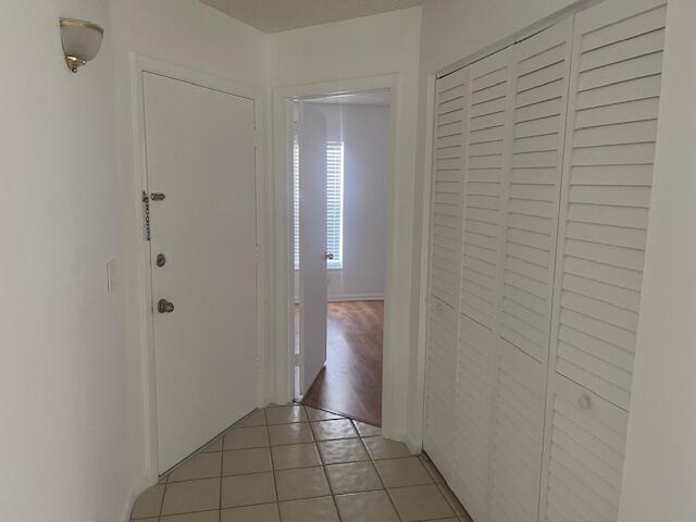 Entryway featuring neutral-toned tile flooring, white bi-fold louvered closet doors, and wall-mounted sconce lighting Entryway featuring neutral-toned tile flooring, white bi-fold louvered closet doors, and wall-mounted sconce lighting