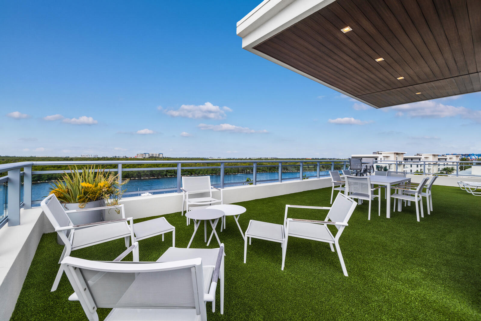 Expansive rooftop terrace featuring synthetic turf, a covered ceiling with recessed lighting, and a metal railing Expansive rooftop terrace featuring synthetic turf, a covered ceiling with recessed lighting, and a metal railing