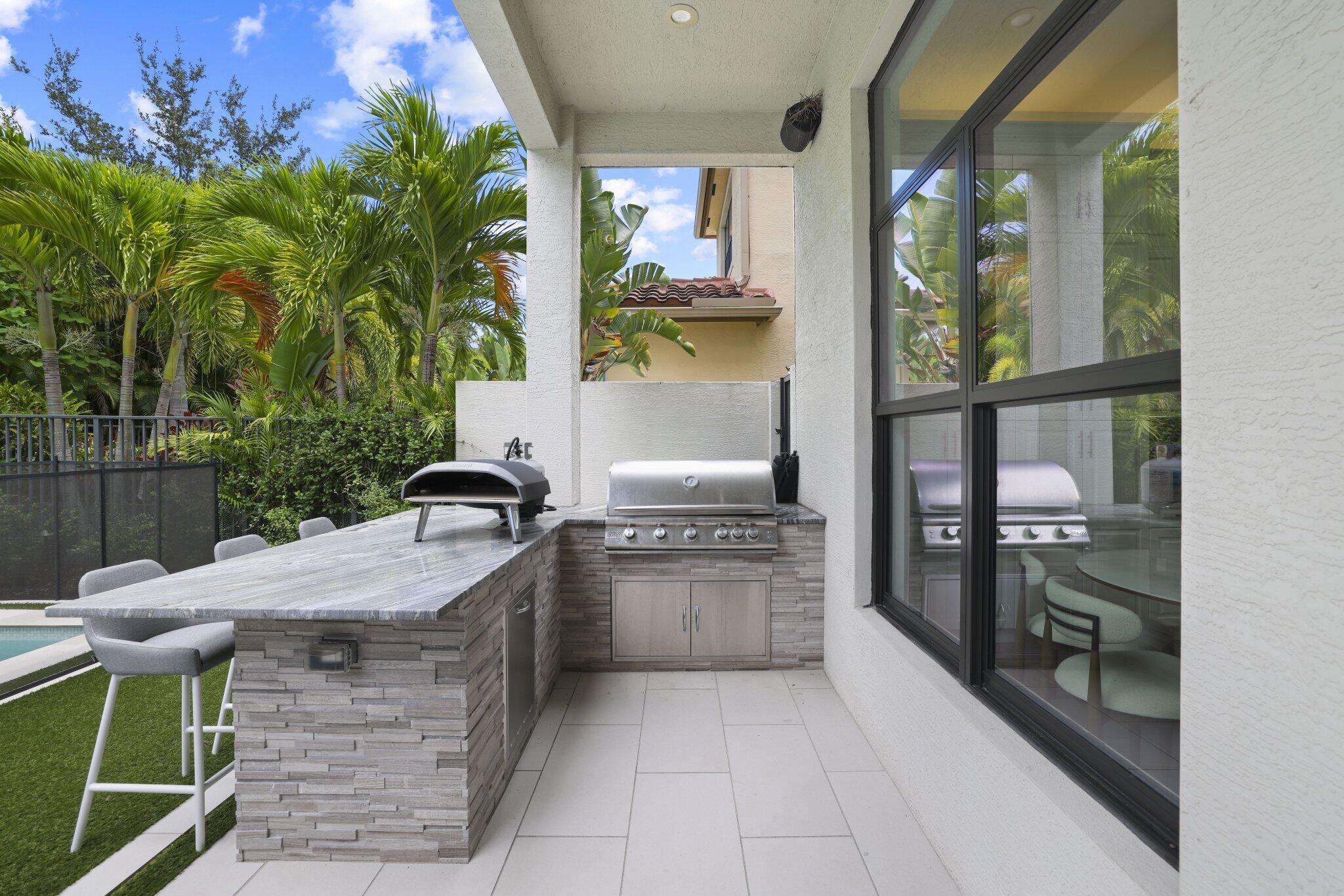 Outdoor kitchen featuring a built-in grill, stone-finish counter, and integrated bar seating