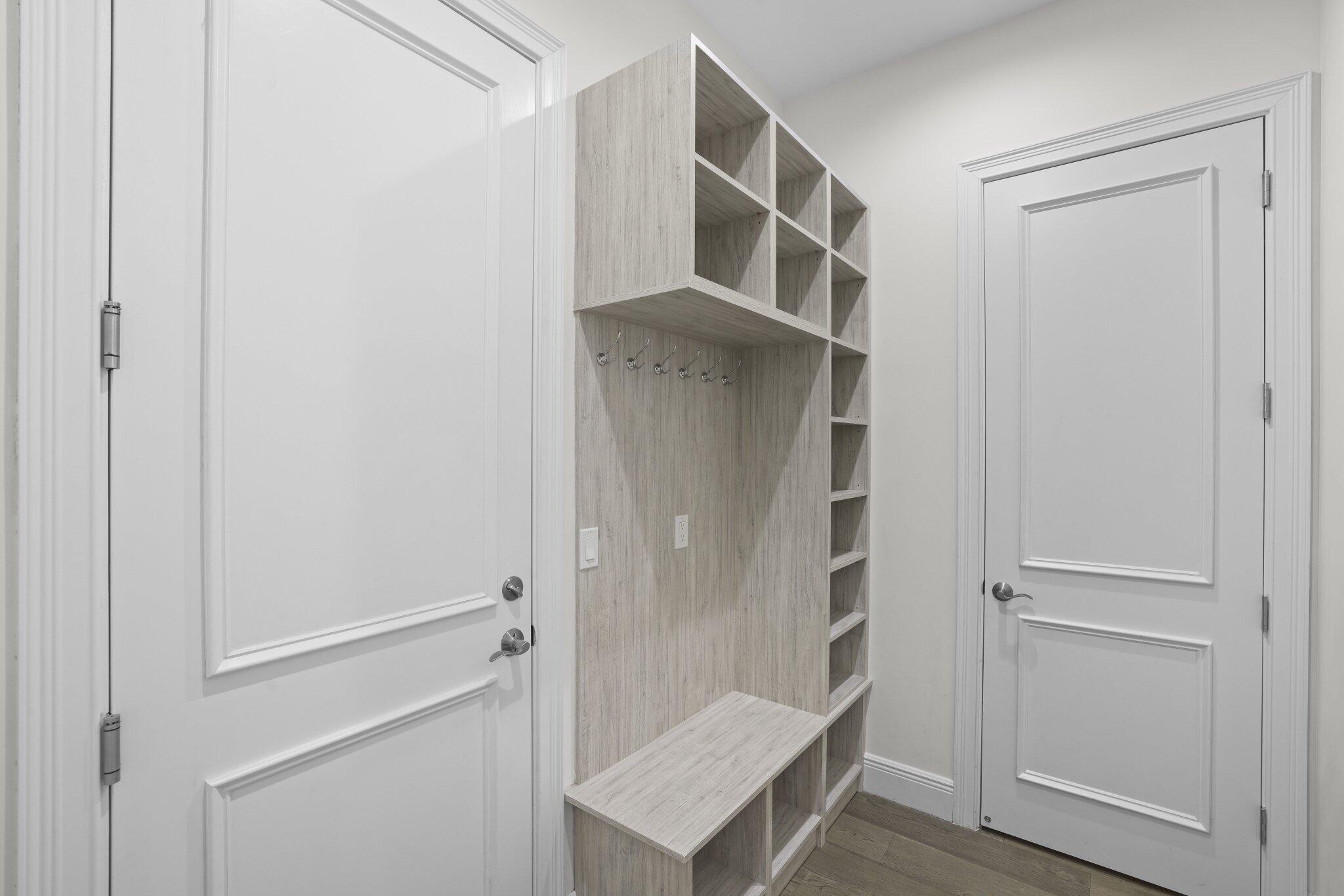 Built-in storage system with cubbies and hooks, engineered wood flooring, and paneled doors