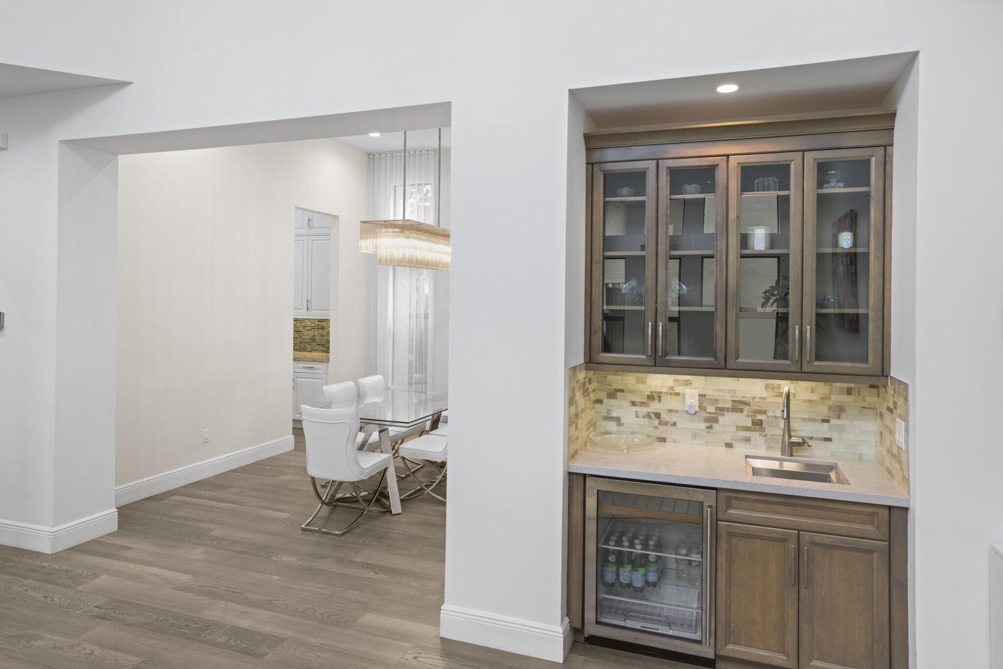 Built-in wet bar with glass-front cabinetry, under-cabinet lighting, and beverage refrigerator