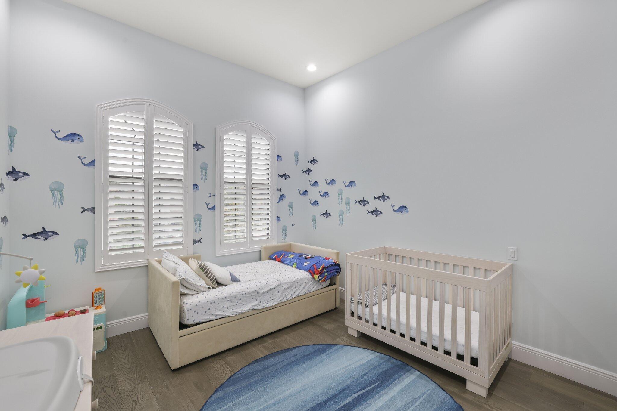Dual arched windows featuring plantation shutters, recessed lighting, and wood-finish flooring