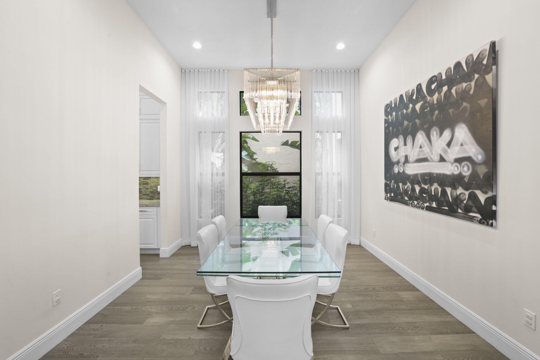 Wood-finish flooring with crisp white baseboards, complemented by a modern chandelier Wood-finish flooring with crisp white baseboards, complemented by a modern chandelier