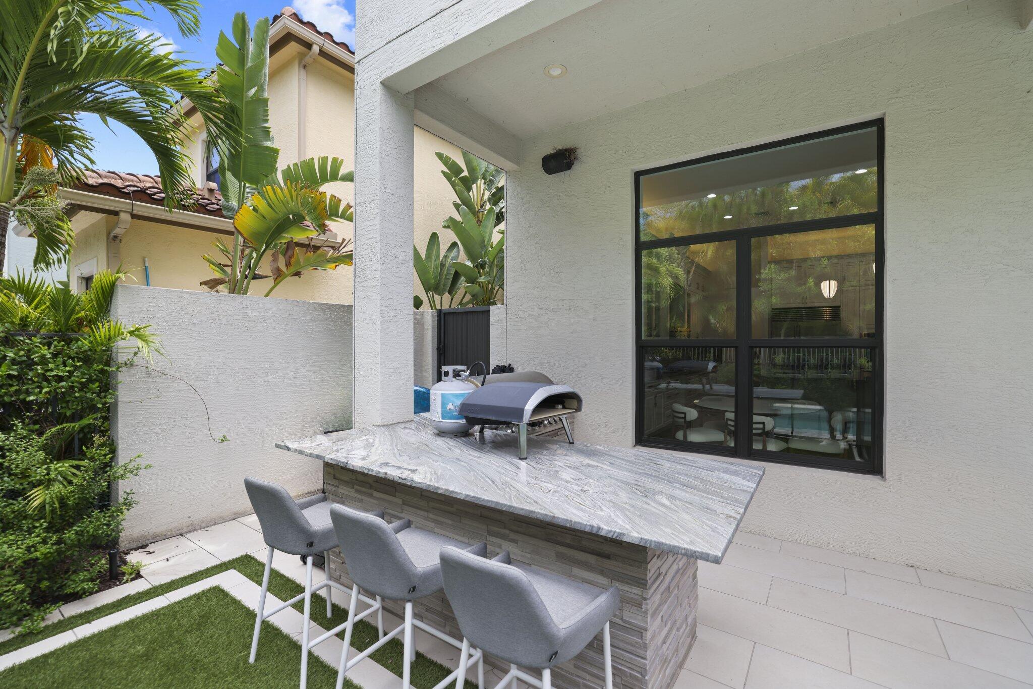 Covered outdoor bar with a stone-finish base, substantial counter, and paved patio