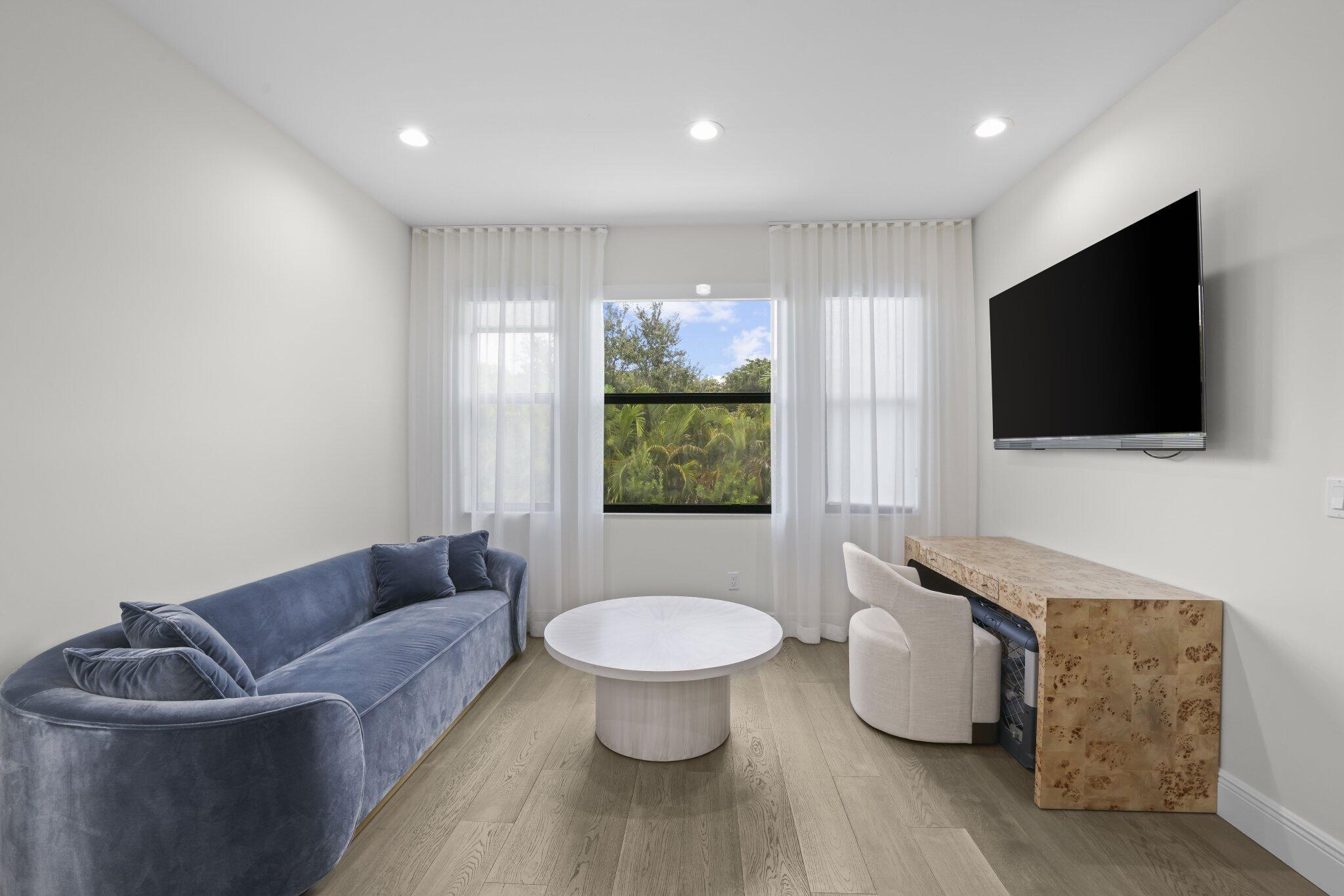 Recessed lighting, wood-finish flooring, multiple windows with sheers, and a built-in console
