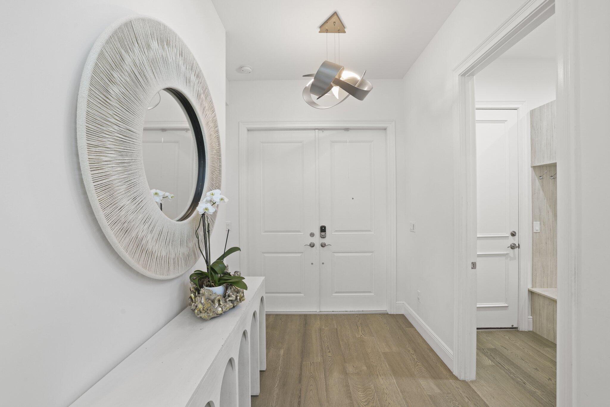 Entryway featuring wood-finish flooring, a modern sculptural pendant light fixture, and white double doors