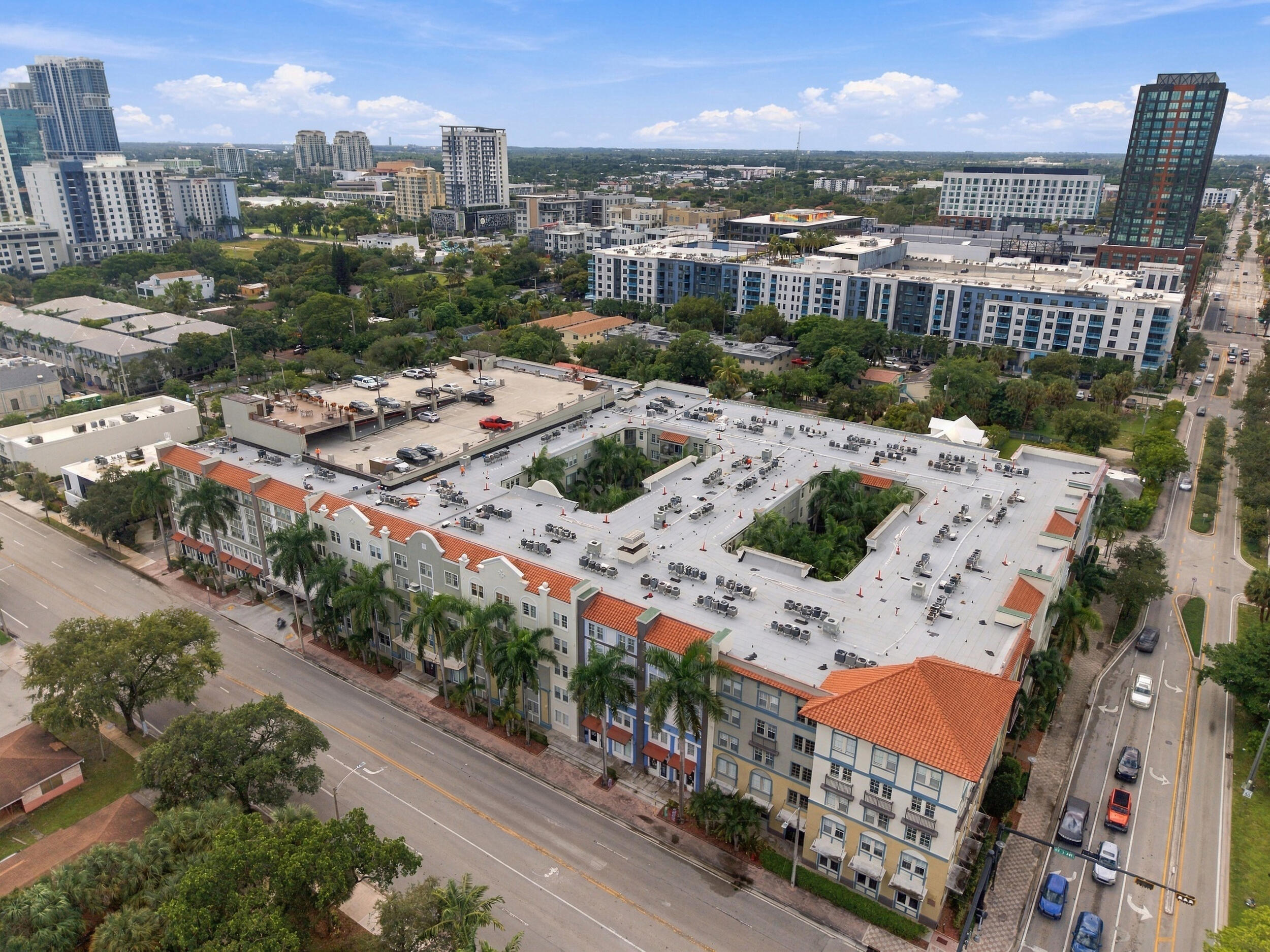 Multi-story complex featuring a terracotta-tiled roof, an interior courtyard, and an attached multi-level parking structure