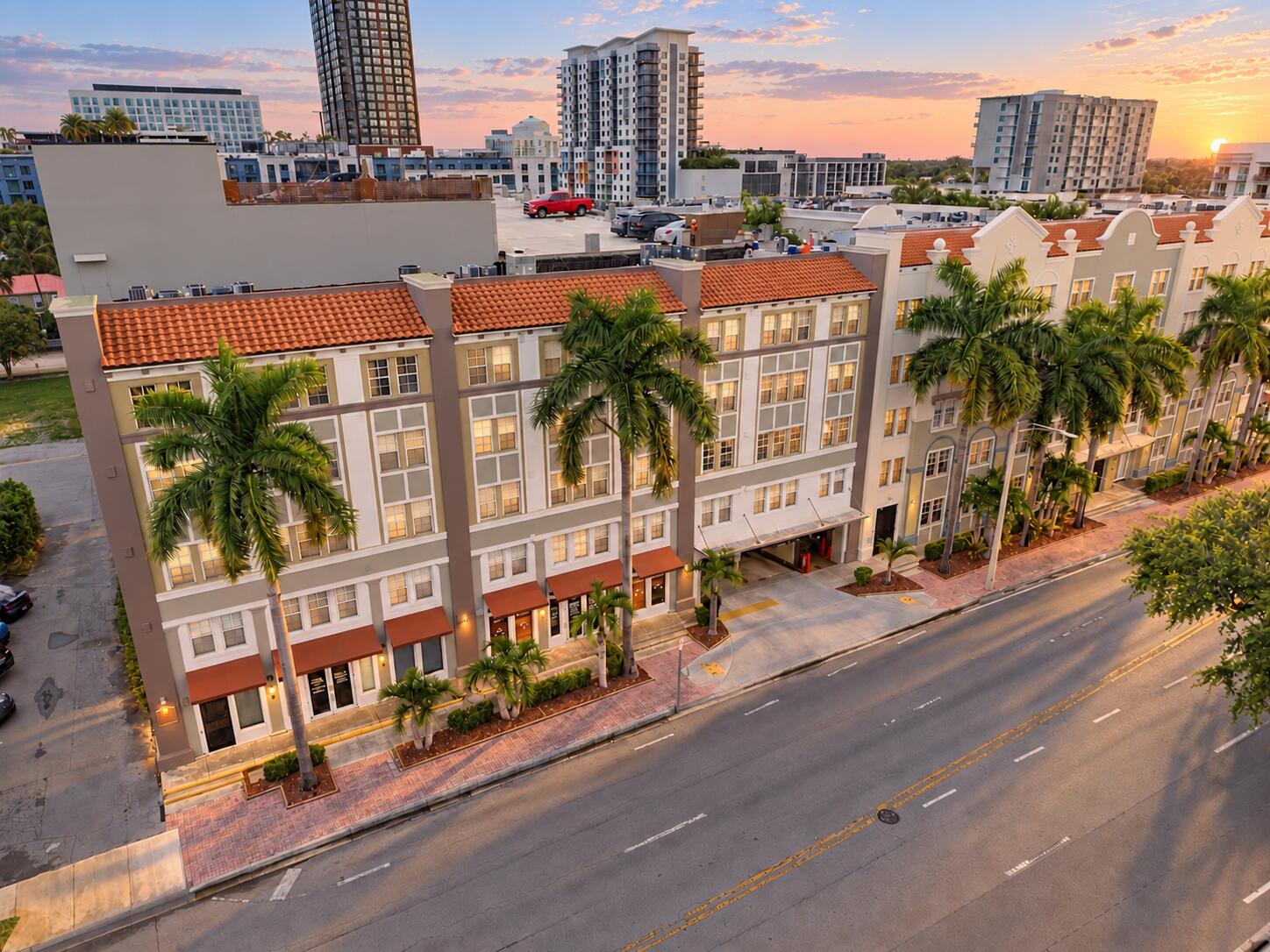 Multi-story exterior featuring terracotta roof tiles, stucco facade, decorative parapets, and integrated ground-level parking