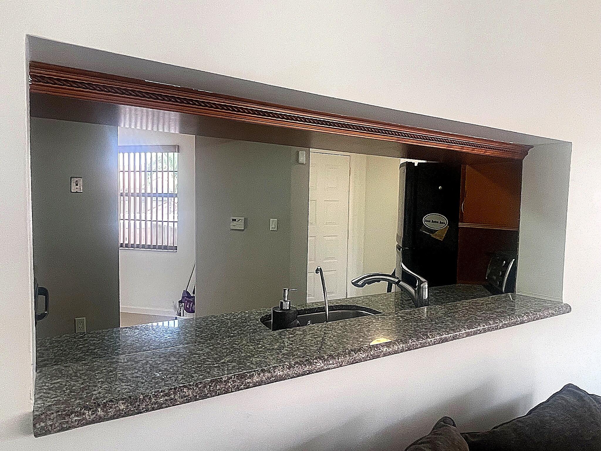 Pass-through window featuring a stone-composite countertop, undermount sink, gooseneck faucet, and stained wood trim detail