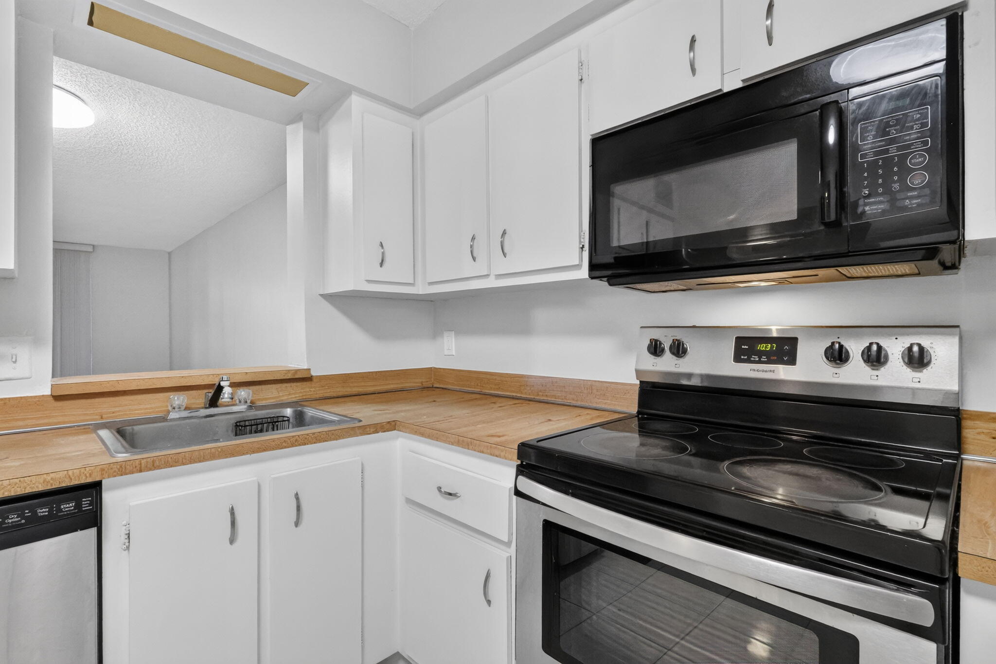 Kitchen featuring white cabinetry, wood-finish countertops, stainless steel sink, and built-in black and stainless steel appliances