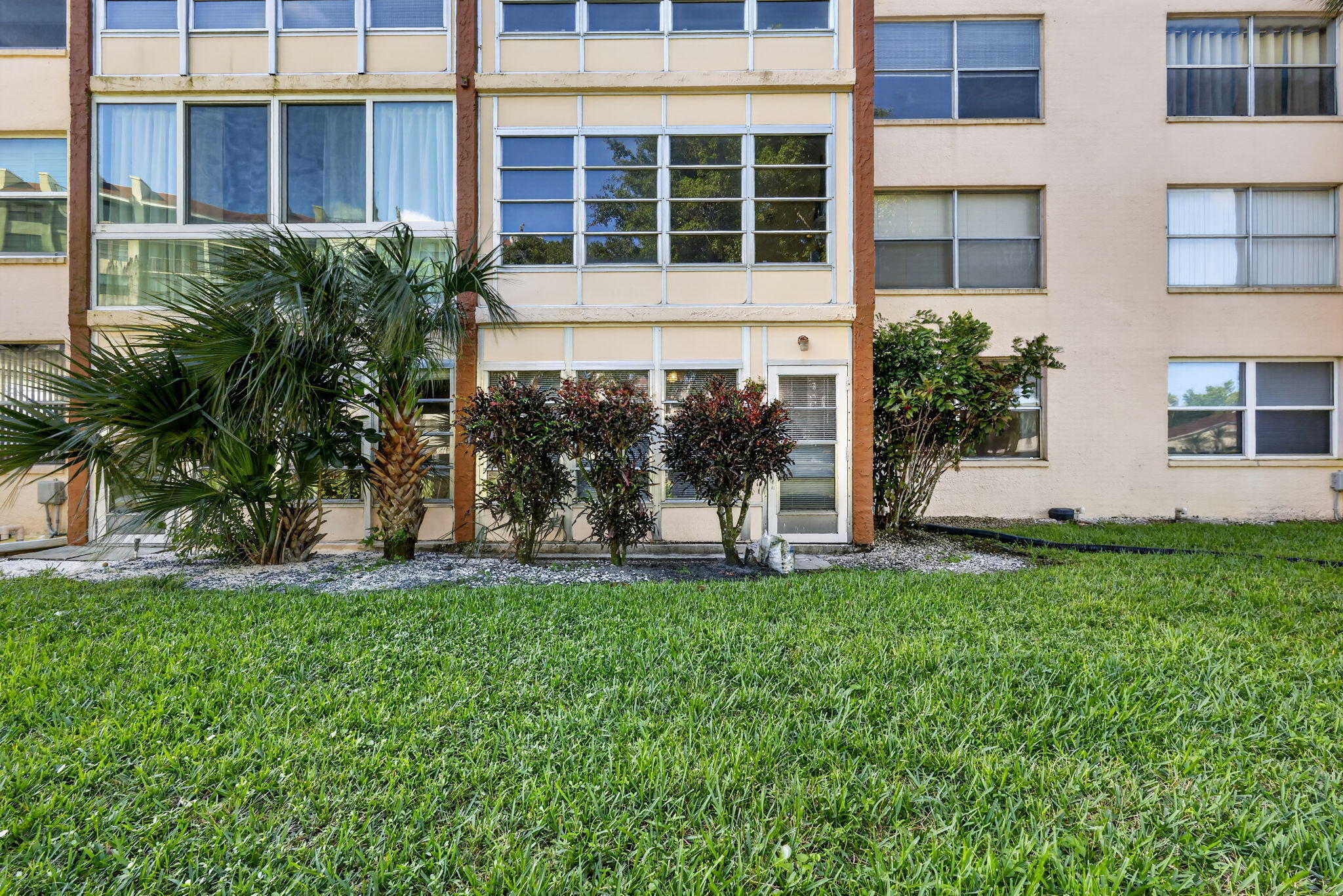 Multi-story exterior featuring a grid-patterned facade, expansive window banks, integrated glass-paneled entry, and manicured landscaping