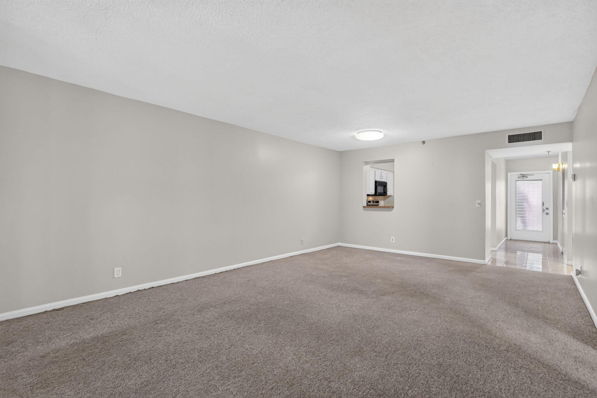 Neutral wall paint, carpeting, ceiling-mounted lighting, and an interior pass-through opening