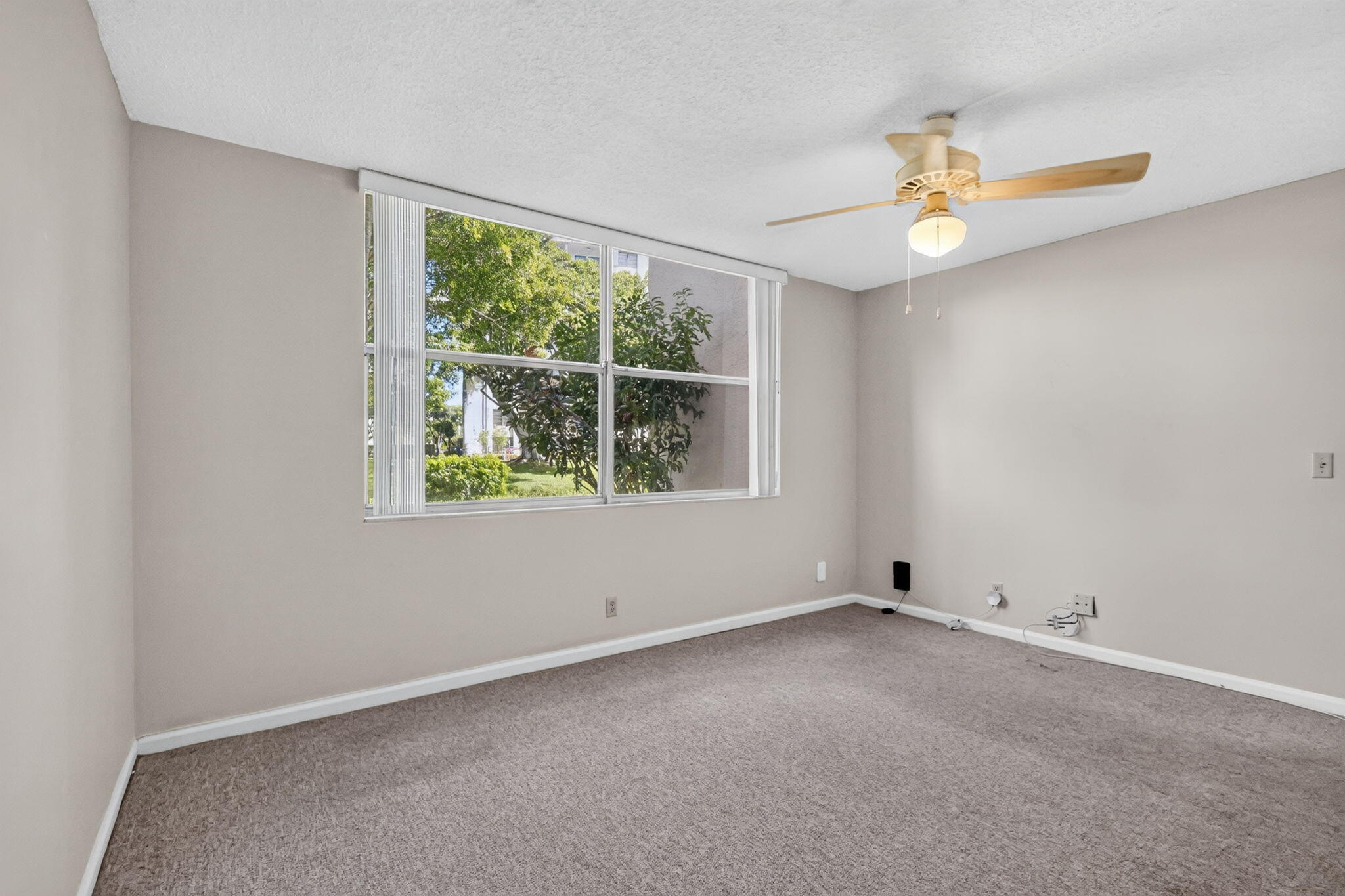Neutral interior featuring wall-to-wall carpeting, a multi-pane window with vertical blinds, and a ceiling-mounted fan with integrated lighting