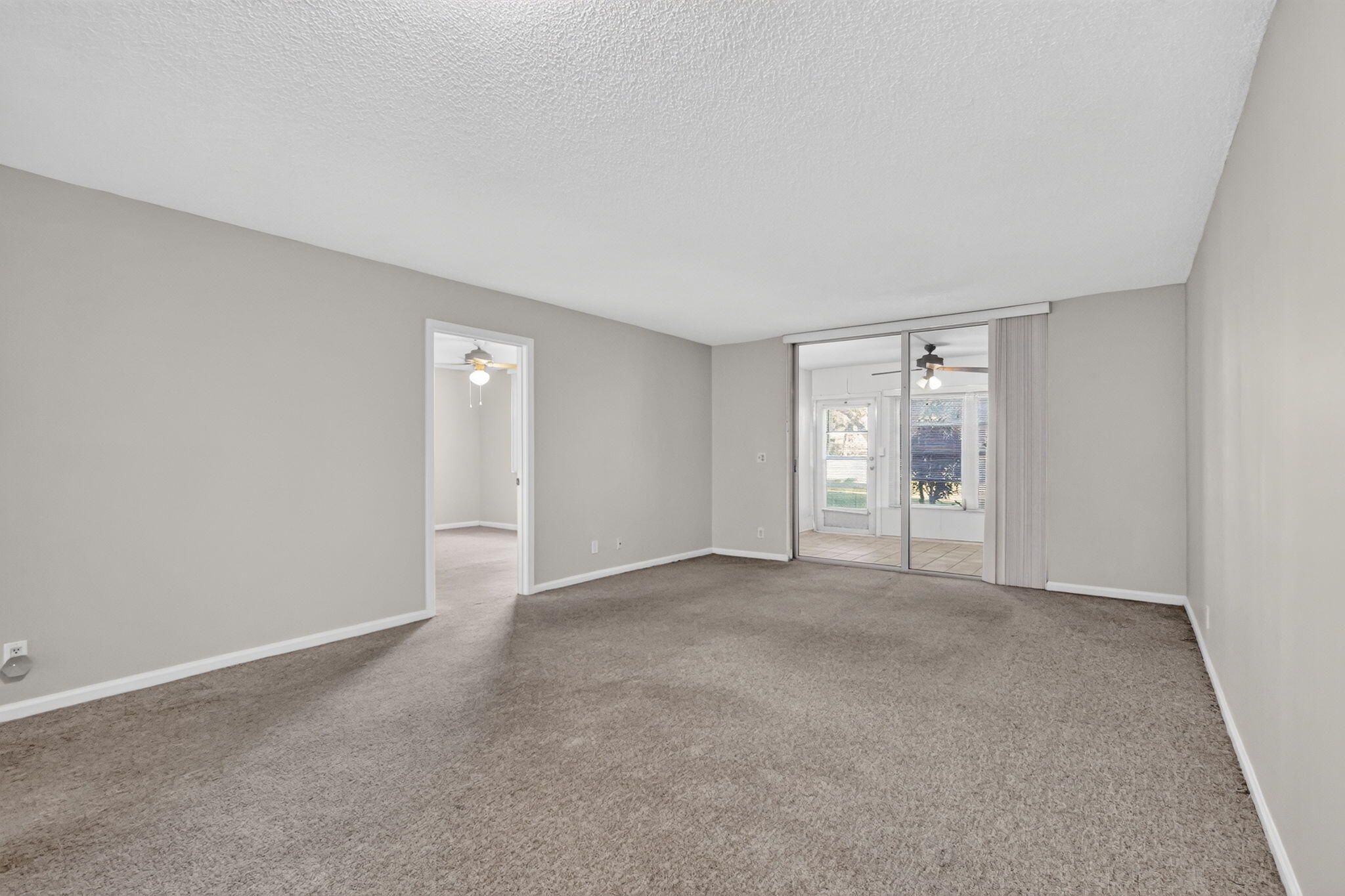 Interior room featuring neutral-toned carpeting, textured ceiling finish, and sliding glass doors