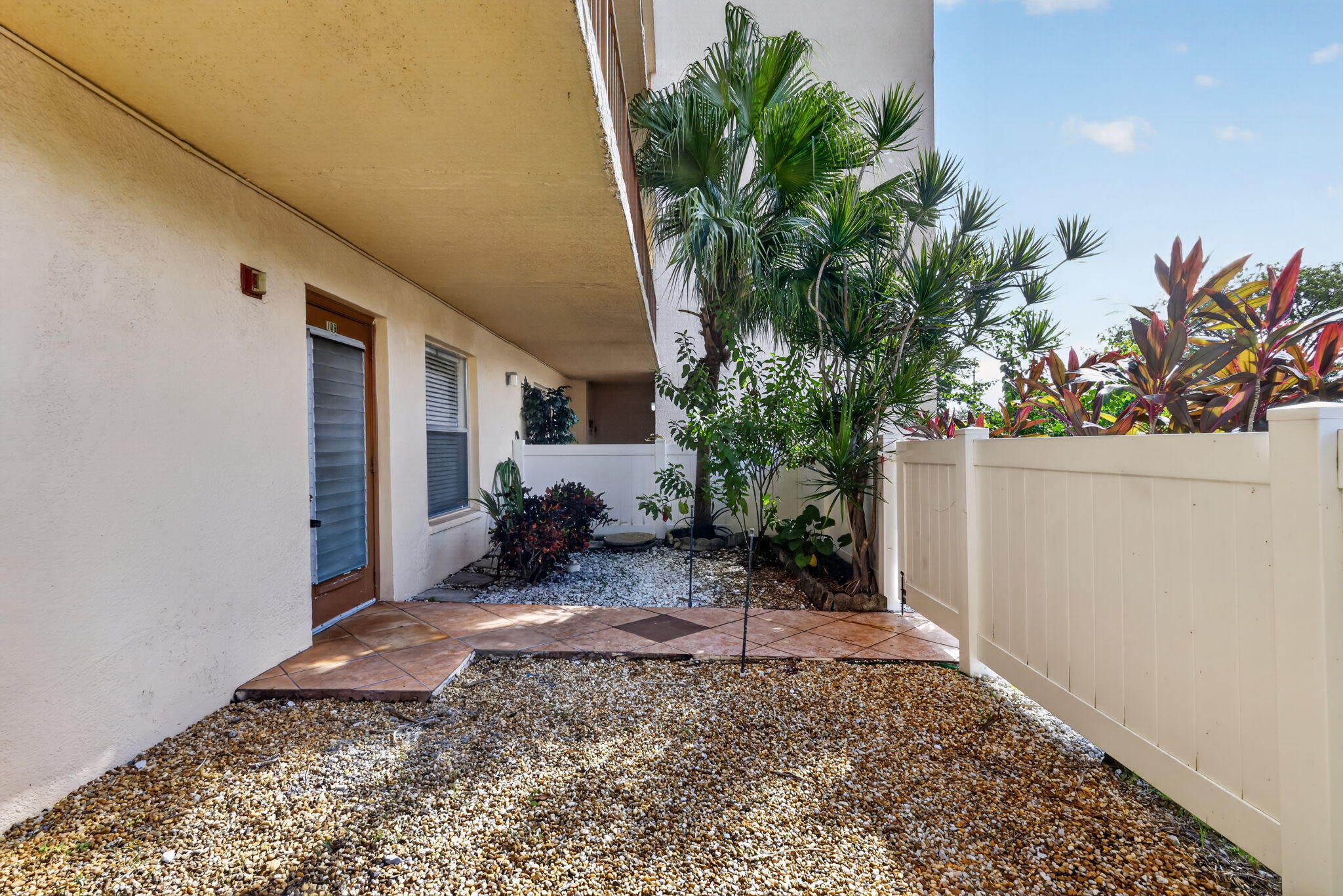 Private patio featuring tile flooring, stone landscaping, and a white privacy fence