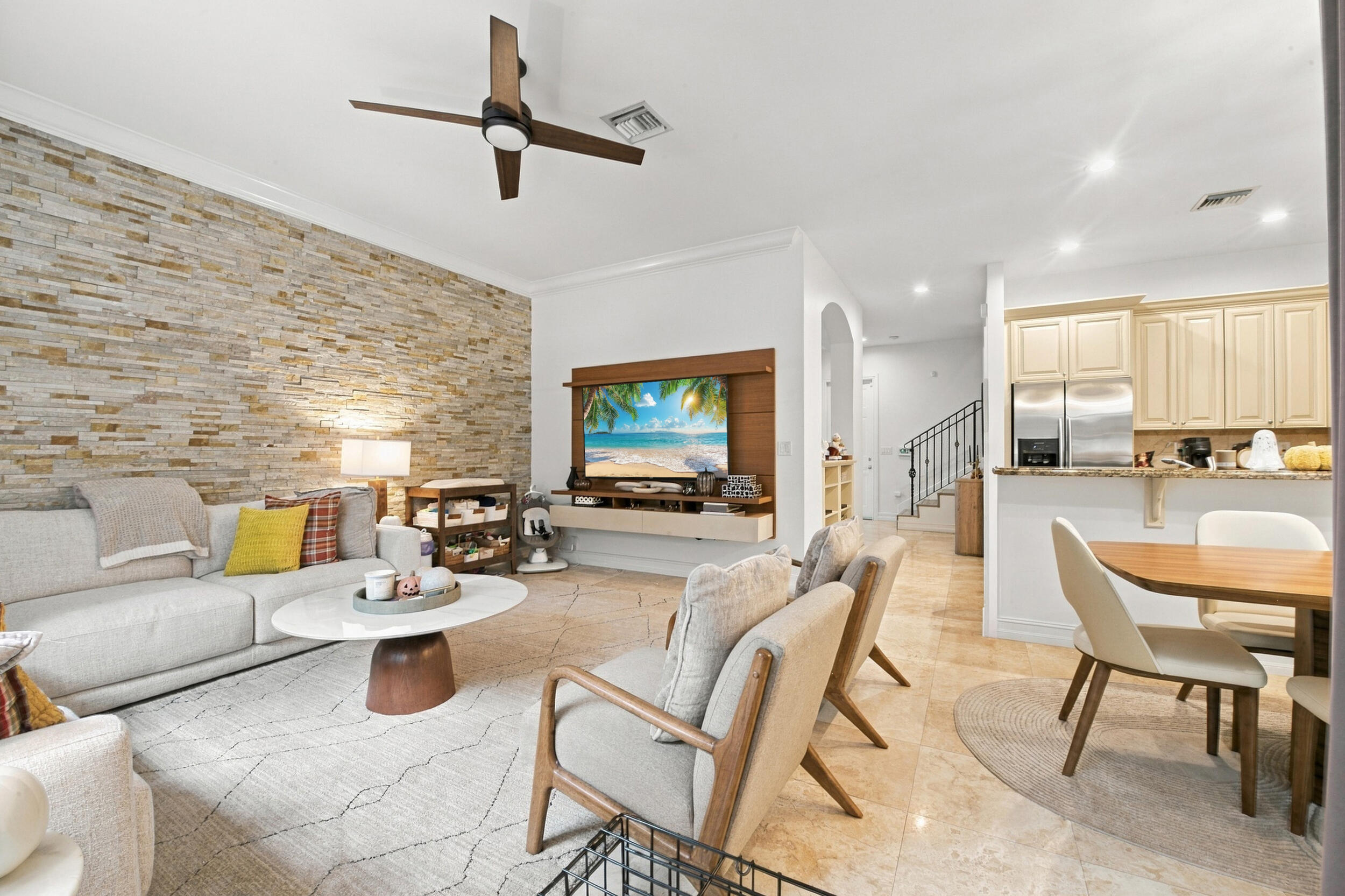 Living area featuring a stacked stone accent wall, tile flooring, built-in wooden media console, recessed lighting, and a ceiling fan