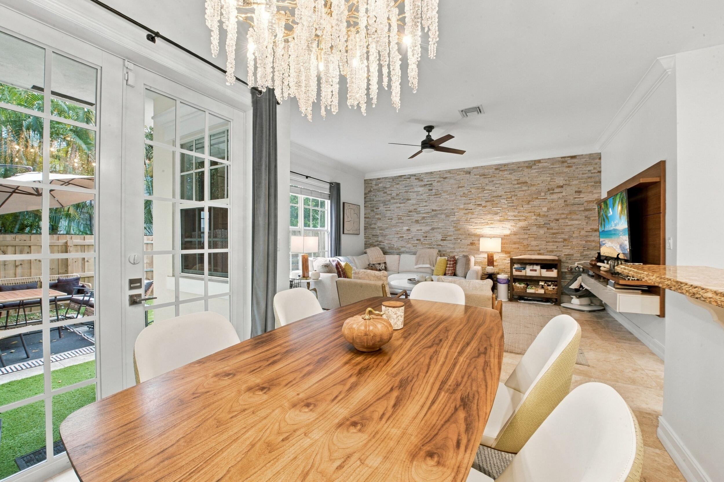 Interior space featuring a stacked stone accent wall, decorative tiered chandelier, French doors with glass panes, crown molding, and neutral tile flooring