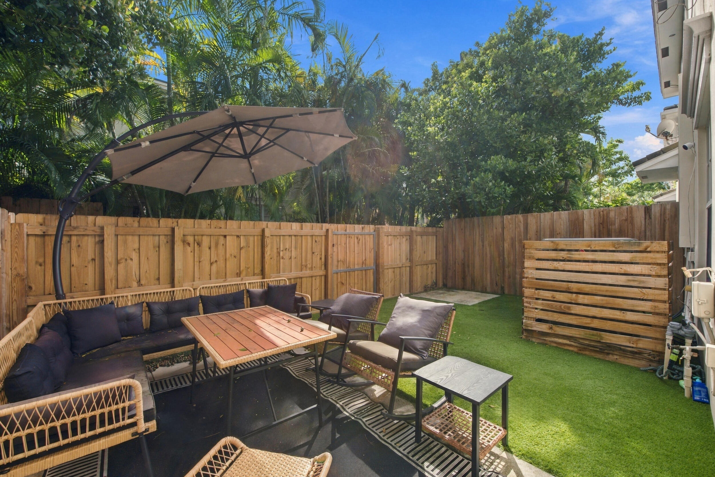 Private backyard featuring wood-panel fencing, synthetic turf, and mature perimeter trees