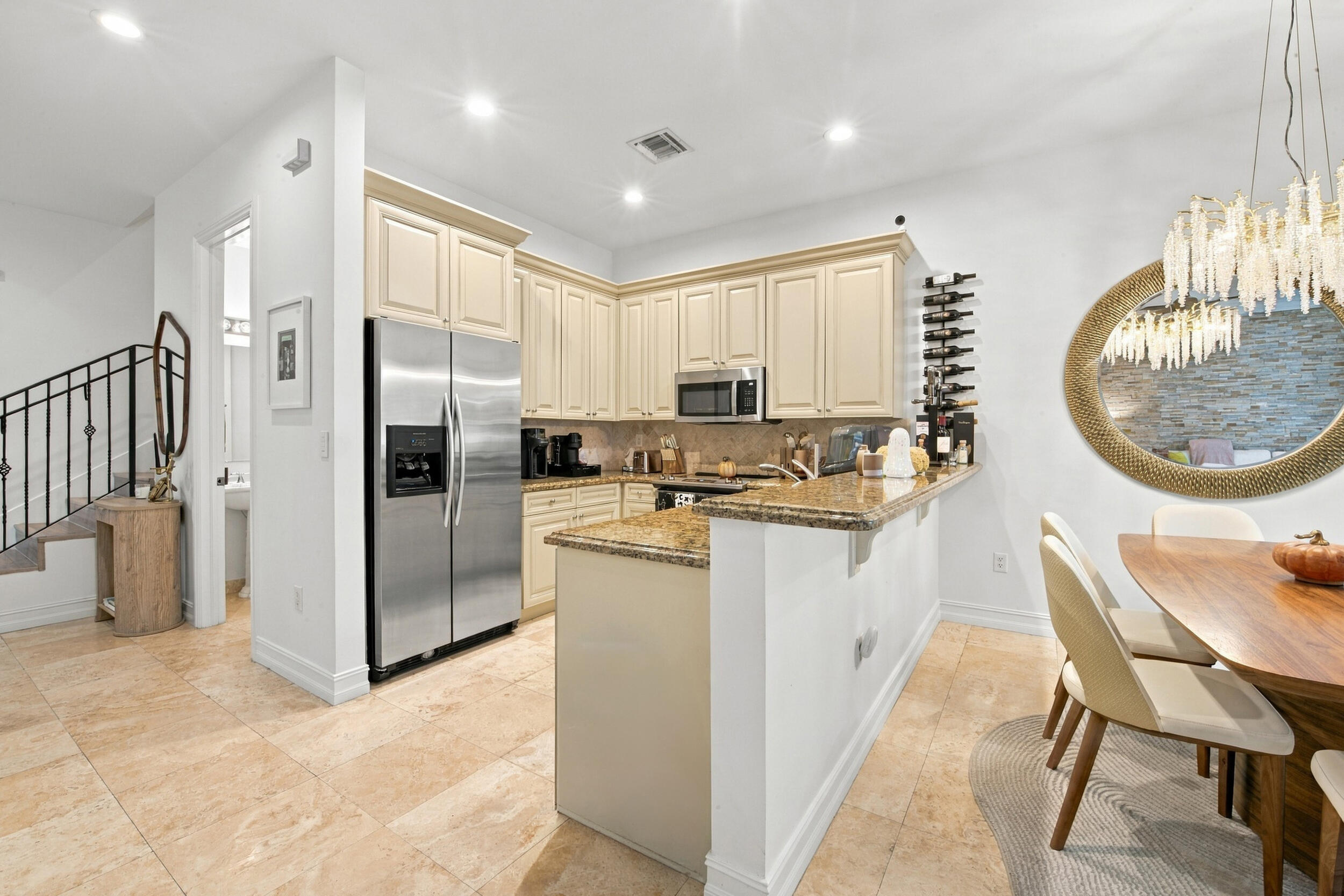 Kitchen featuring stone countertops, stainless steel refrigerator, stone flooring, recessed lighting, and crown-molded cabinetry