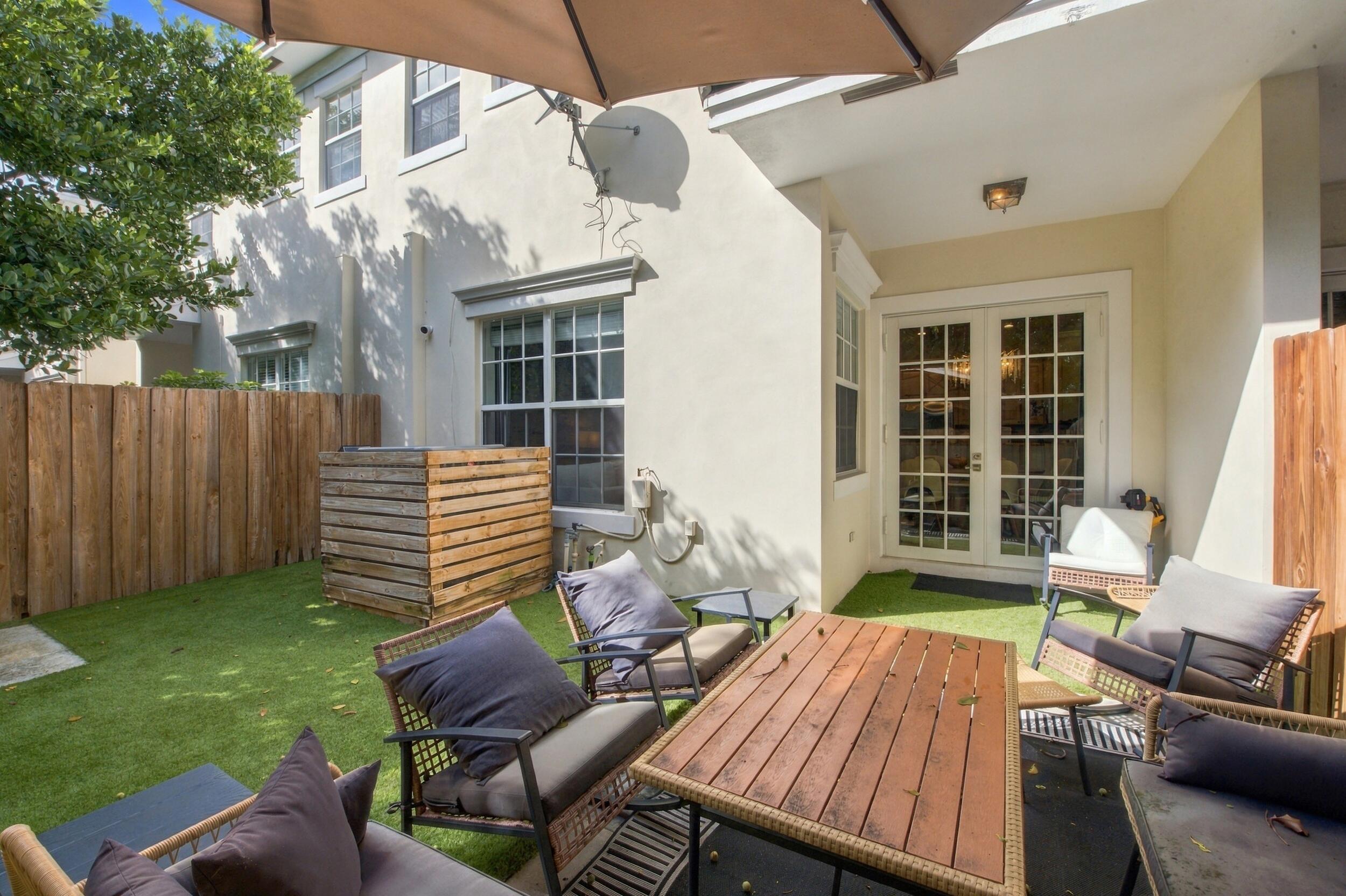 Private backyard featuring synthetic turf, wood-slat privacy fencing, a covered patio area, and French doors