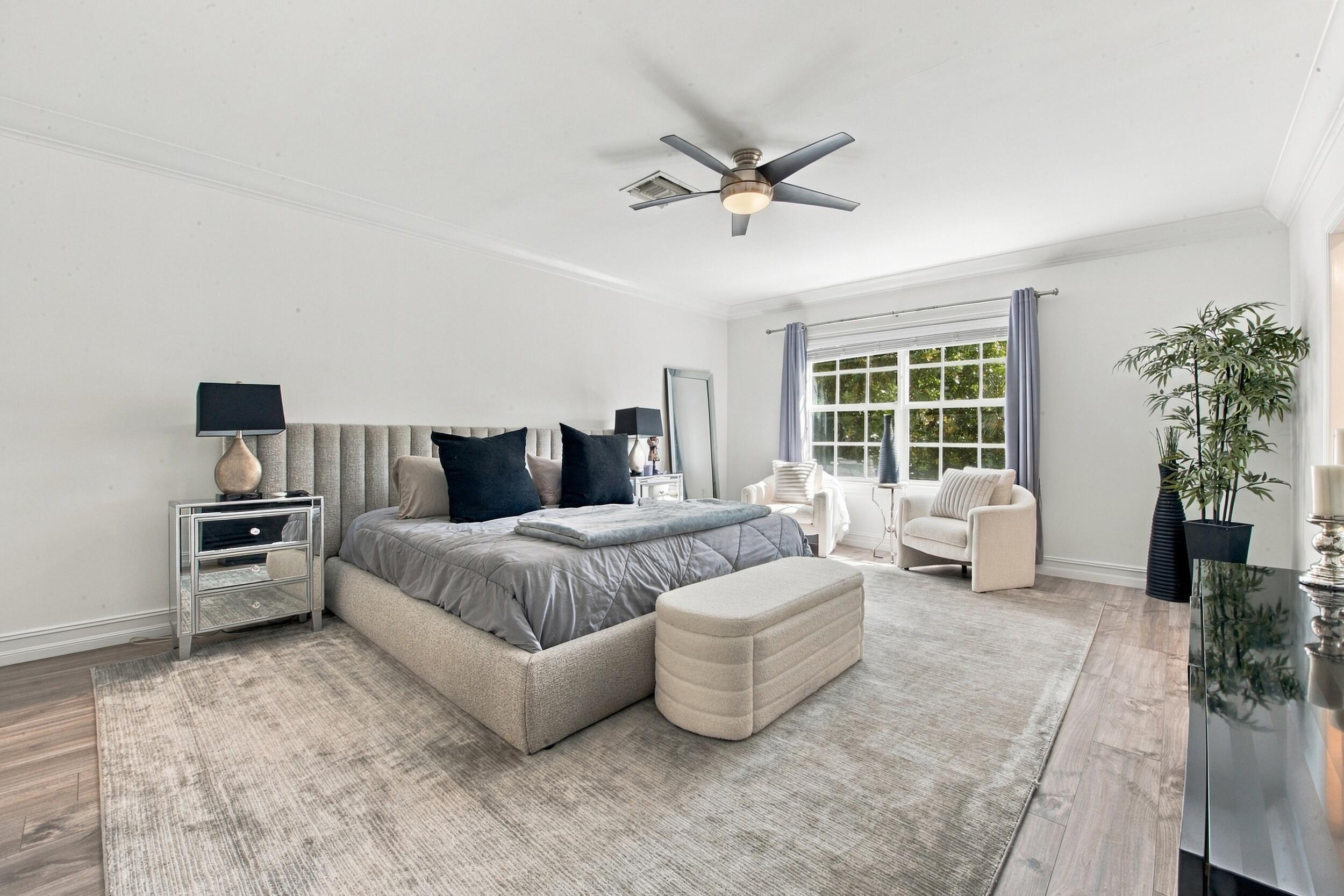 Bedroom featuring wood-finish flooring, multi-pane window, crown molding, and a central ceiling fan with integrated lighting