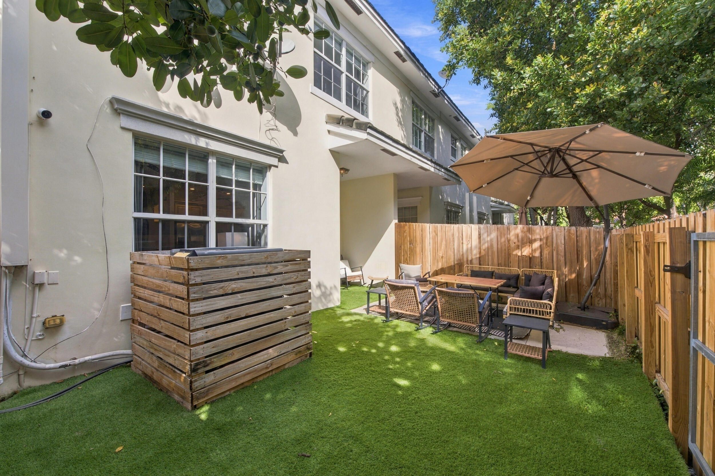 Private fenced backyard featuring low-maintenance synthetic turf and a paved patio area