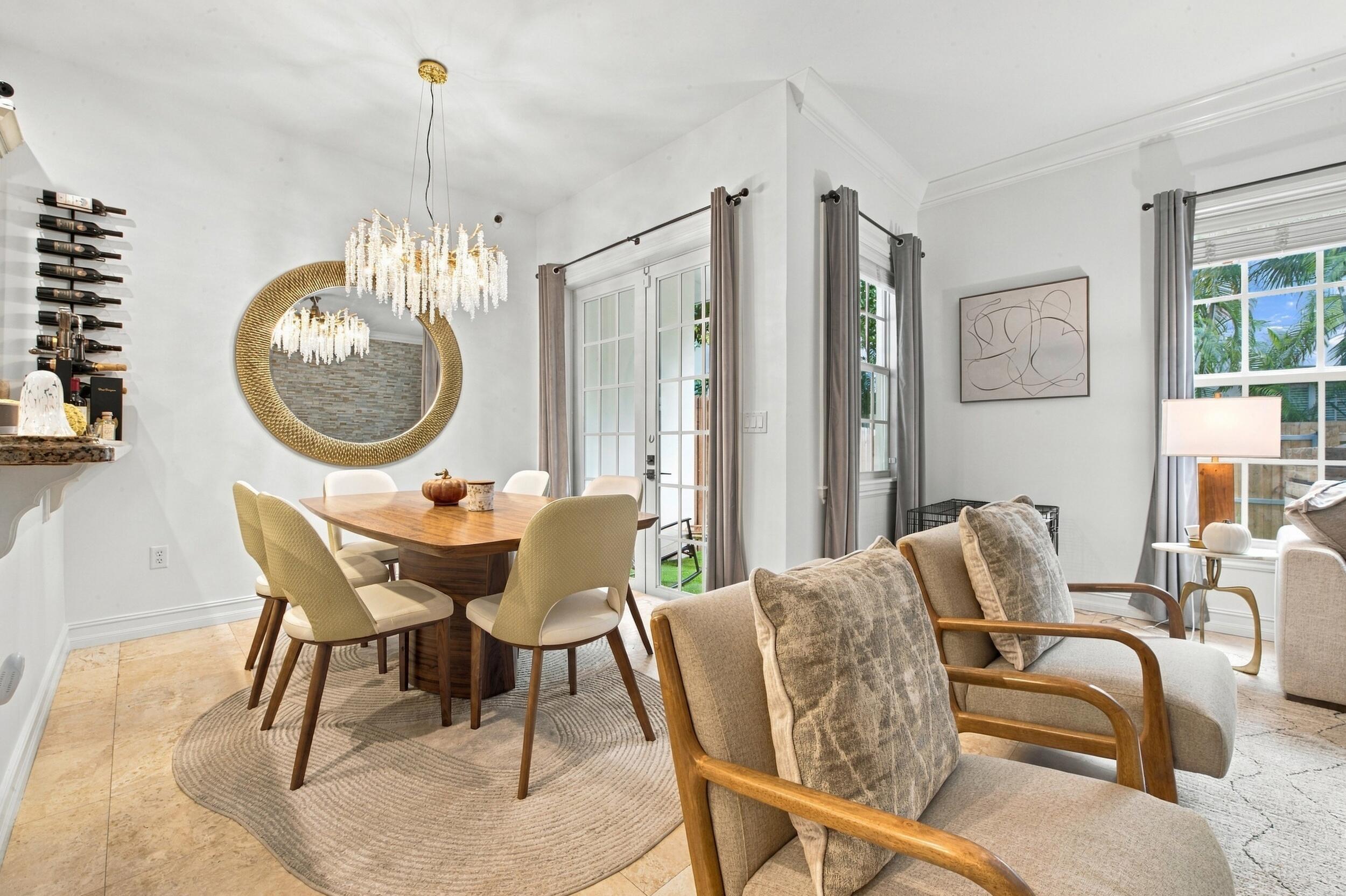 Dining area featuring neutral stone flooring, crown molding, a multi-tiered crystal chandelier, and glass-paned French doors
