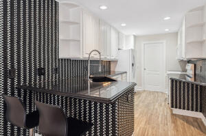 Kitchen featuring white cabinetry, wood-finish flooring, patterned tile backsplash, recessed lighting, and a dark stone-surface countertop with an undermount sink