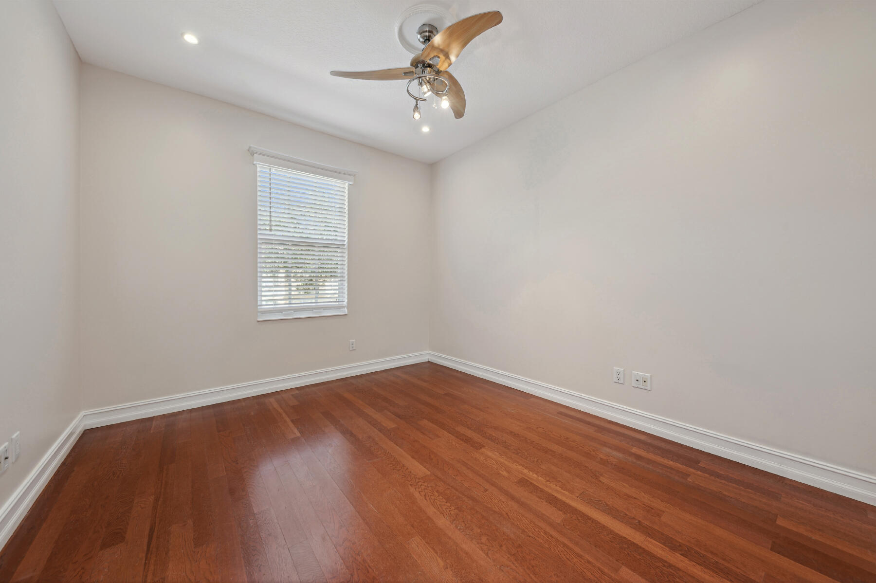 Room featuring wood-finish flooring, recessed lighting, and a three-blade ceiling fan with integrated lighting